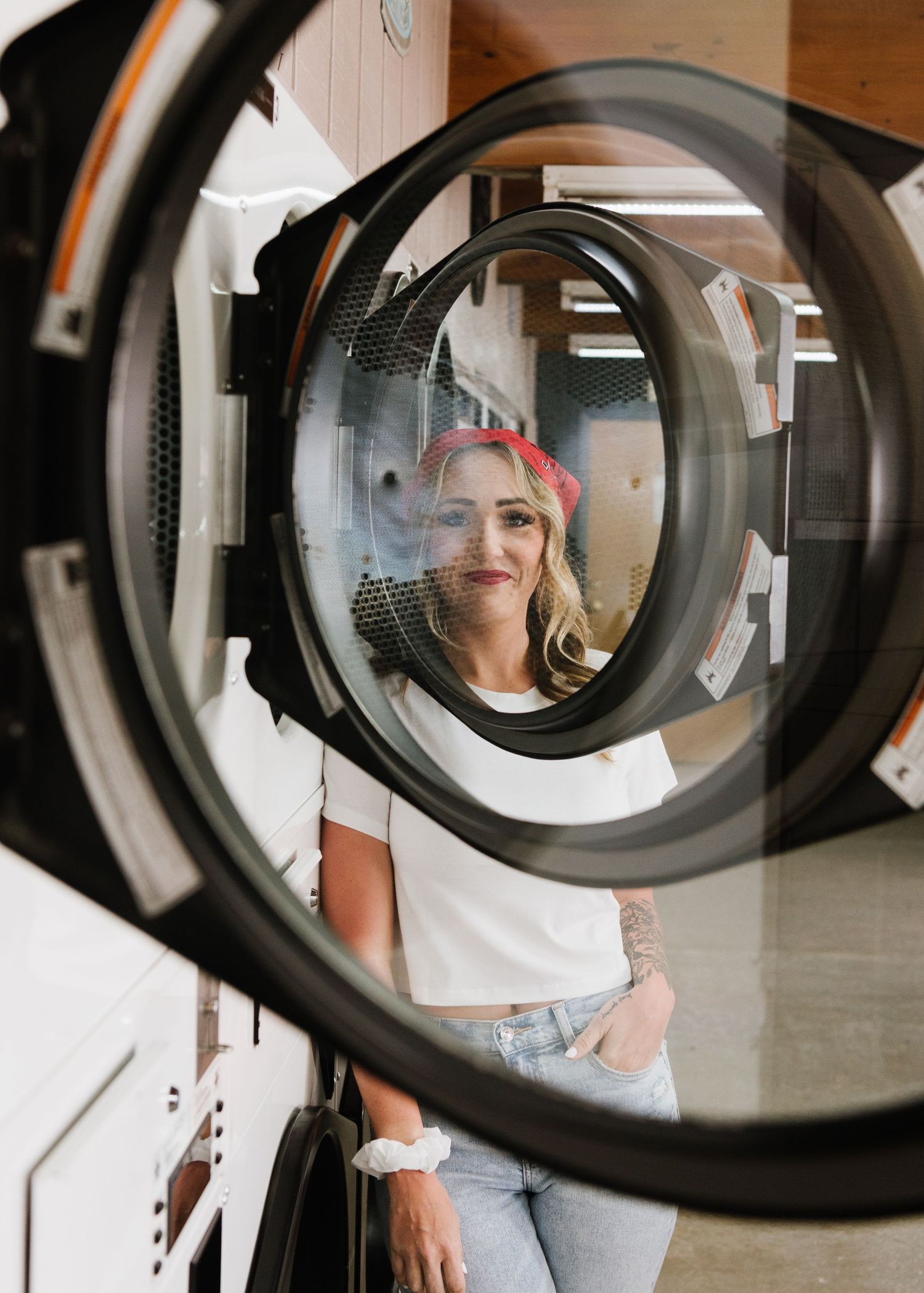 View through circular laundry dryer door showing reflection in light, casual setting.