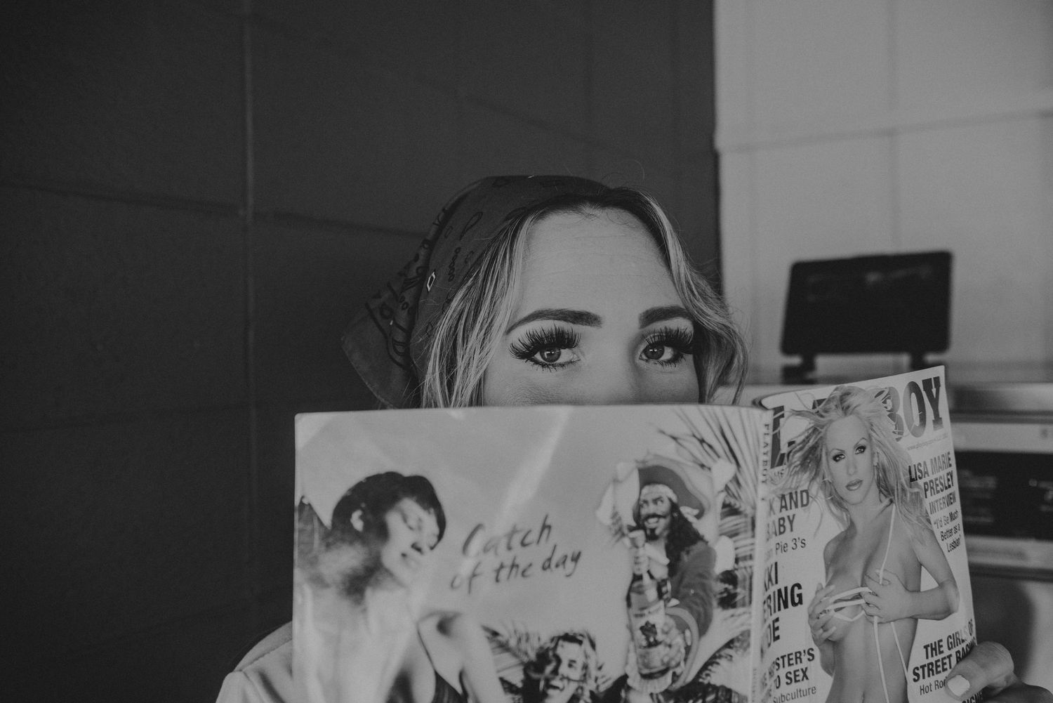 Someone holds up a manga comic book in black and white while reading behind it.