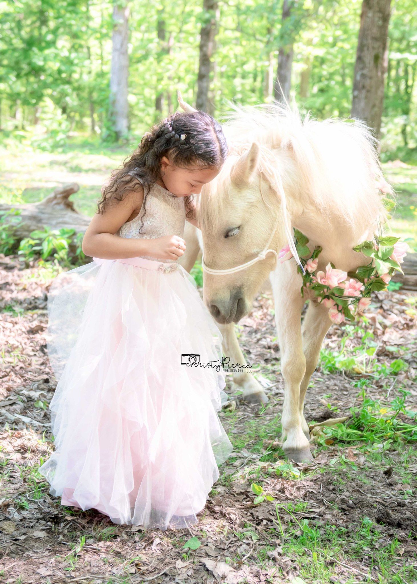 A magical forest scene with a dreamy pink tulle dress and a gentle cream-colored pony surrounded by lush greenery.