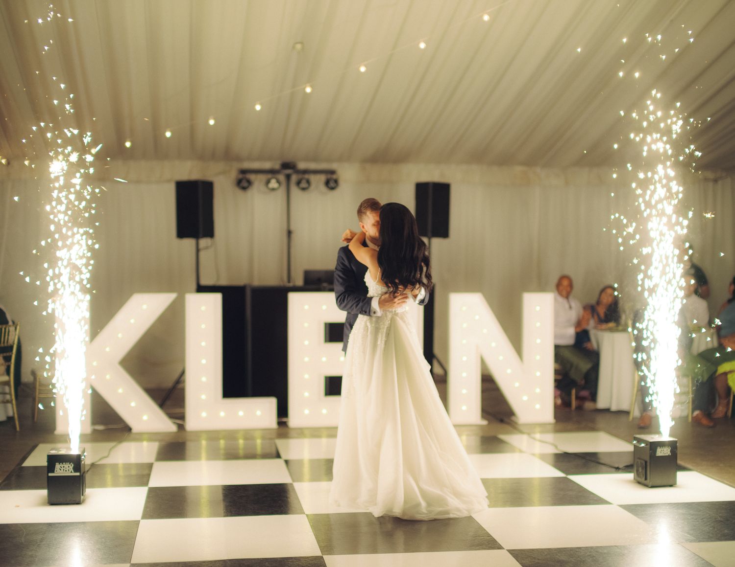A first dance moment in front of illuminated KLEAN letters with sparkler effects.