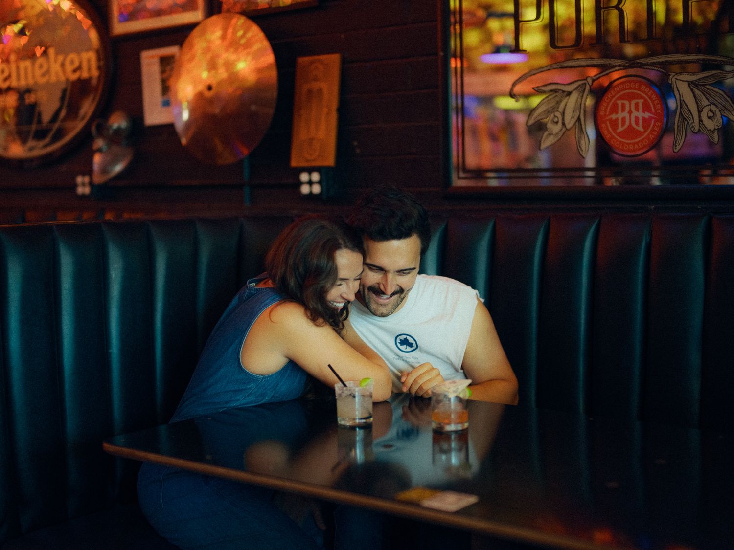 Intimate moment shared at a cozy bar booth with ambient lighting.