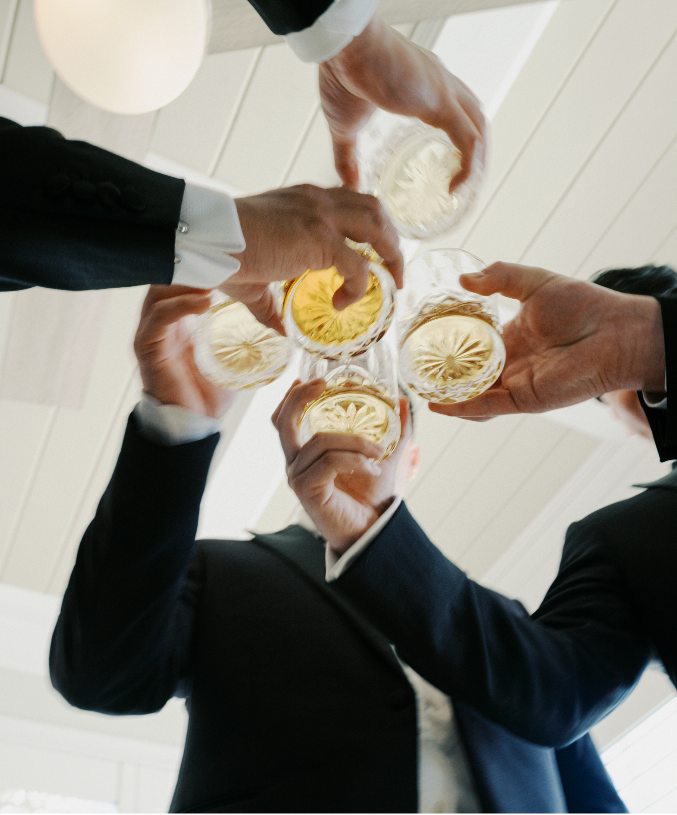 Business colleagues in formal attire toasting with champagne glasses in a circle from overhead view.