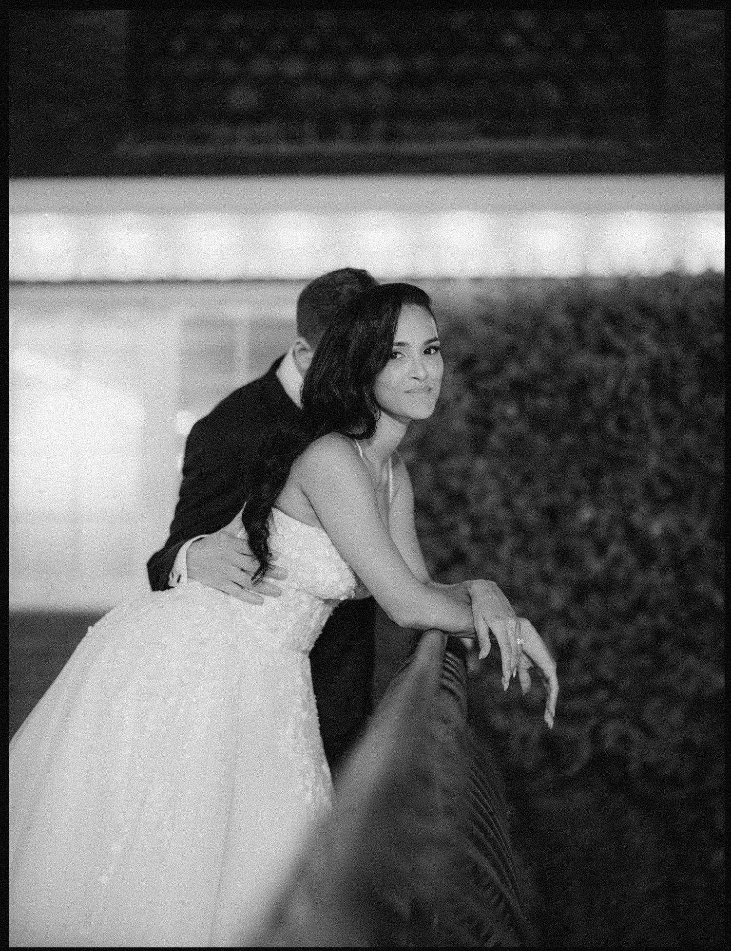 Elegant black and white wedding portrait against a textured wall.