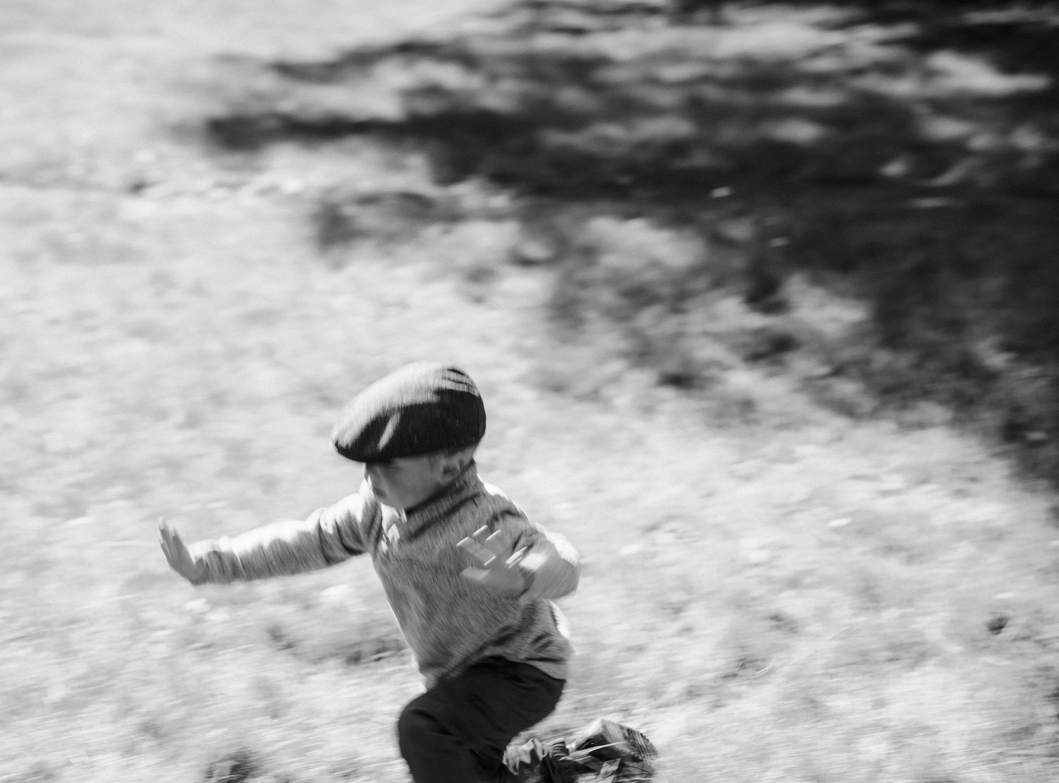 Black and white image of a child playing outdoors in motion.