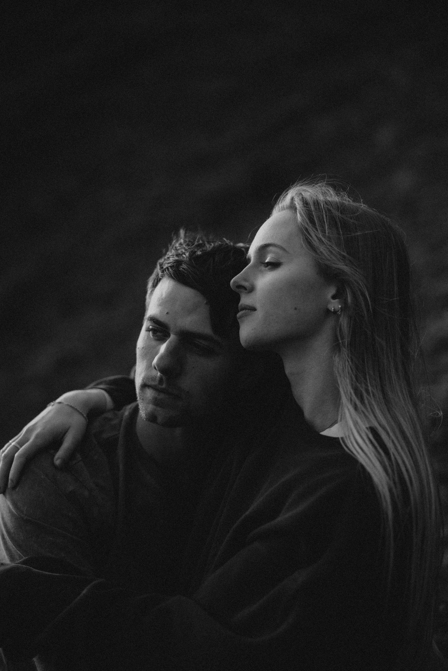 An intimate black and white portrait of a couple sharing a tender moment.
