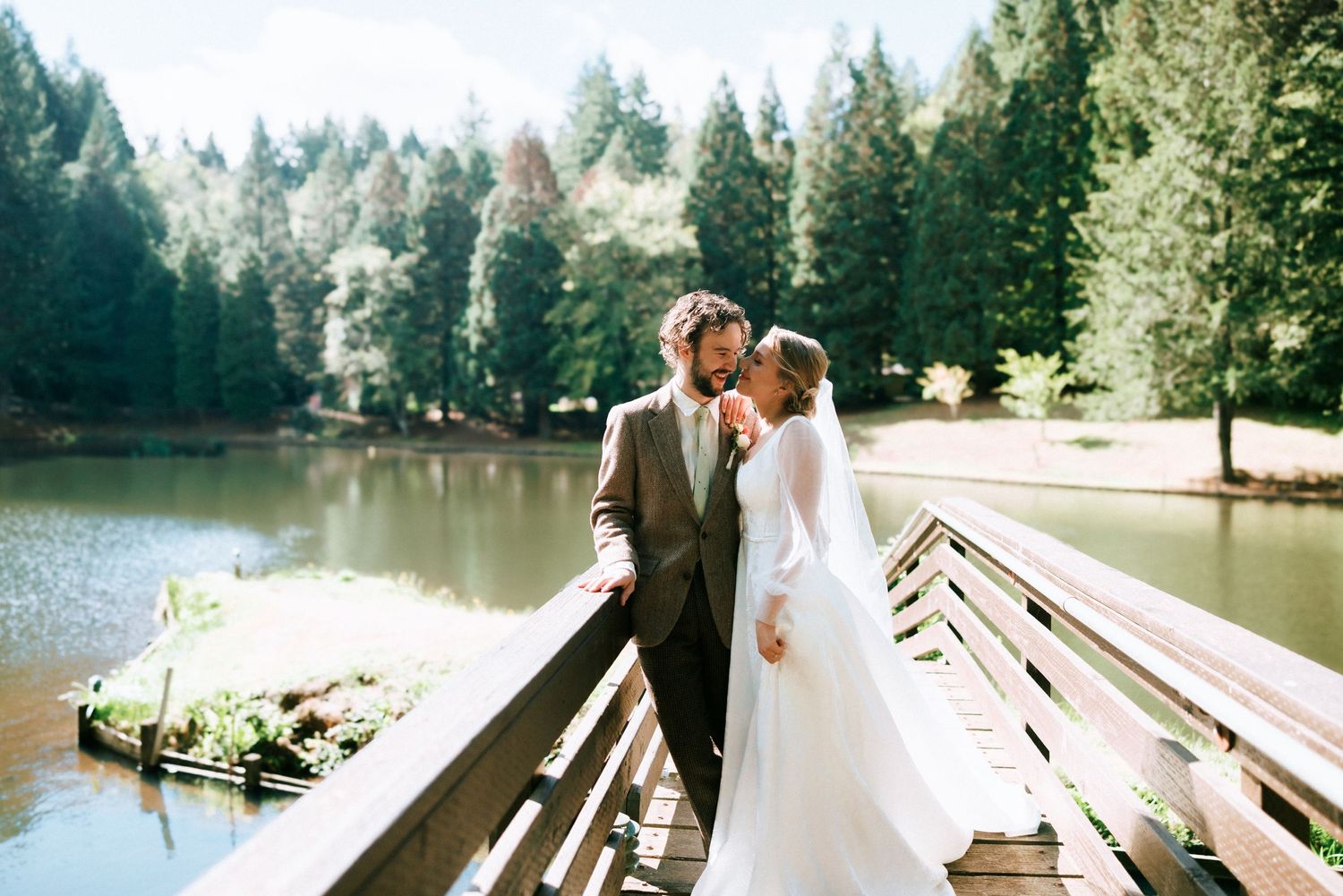 A romantic moment shared on a wooden dock overlooking a serene lake surrounded by evergreen trees.