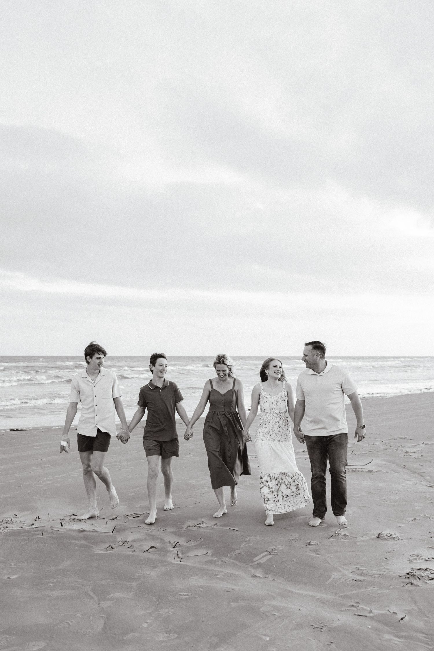 Group walking together along beach shoreline in black and white photography.