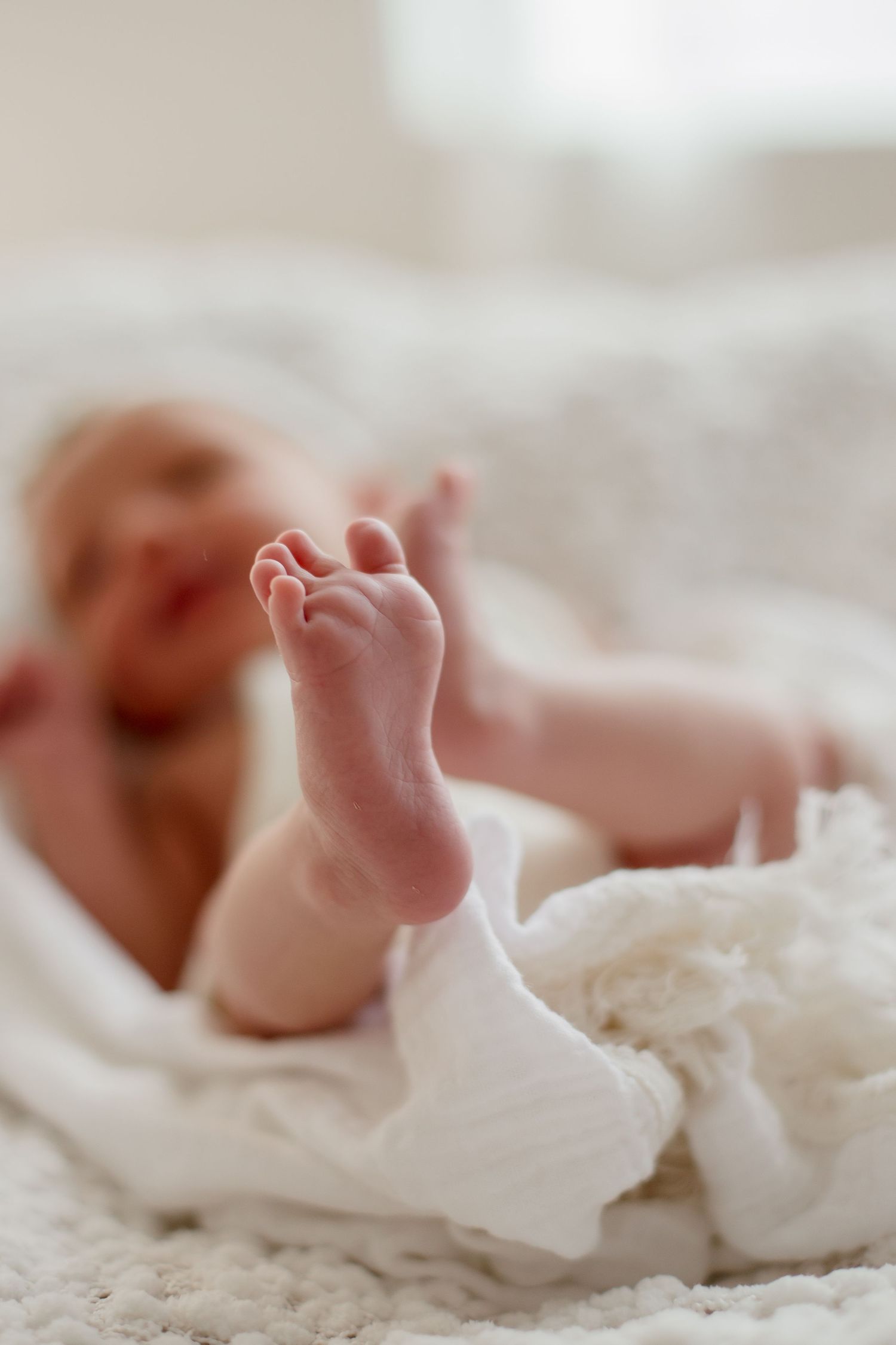 Close-up of tiny baby feet against soft white blanket.