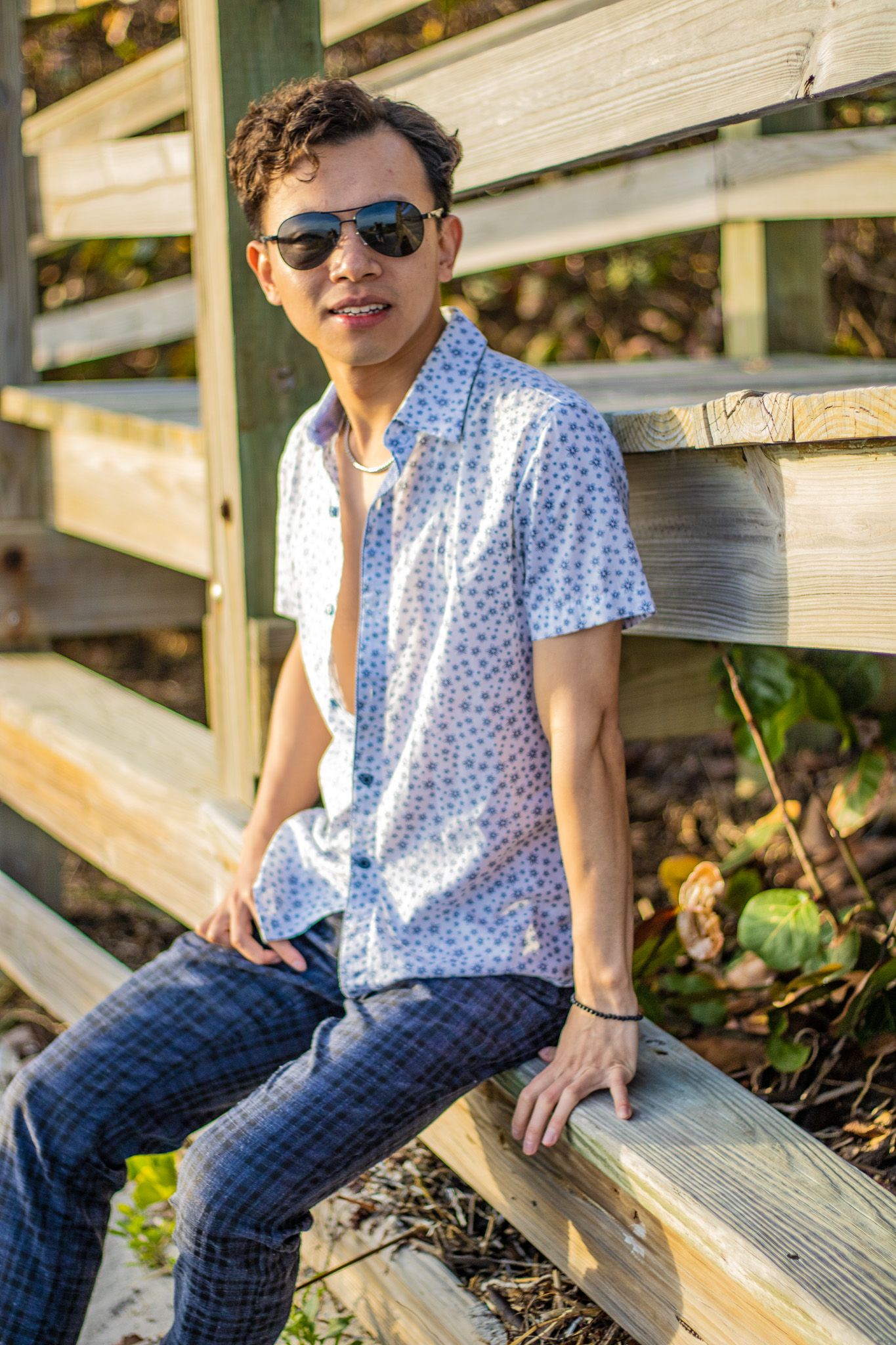Summer style portrait on beach boardwalk with sunglasses and blue floral shirt.