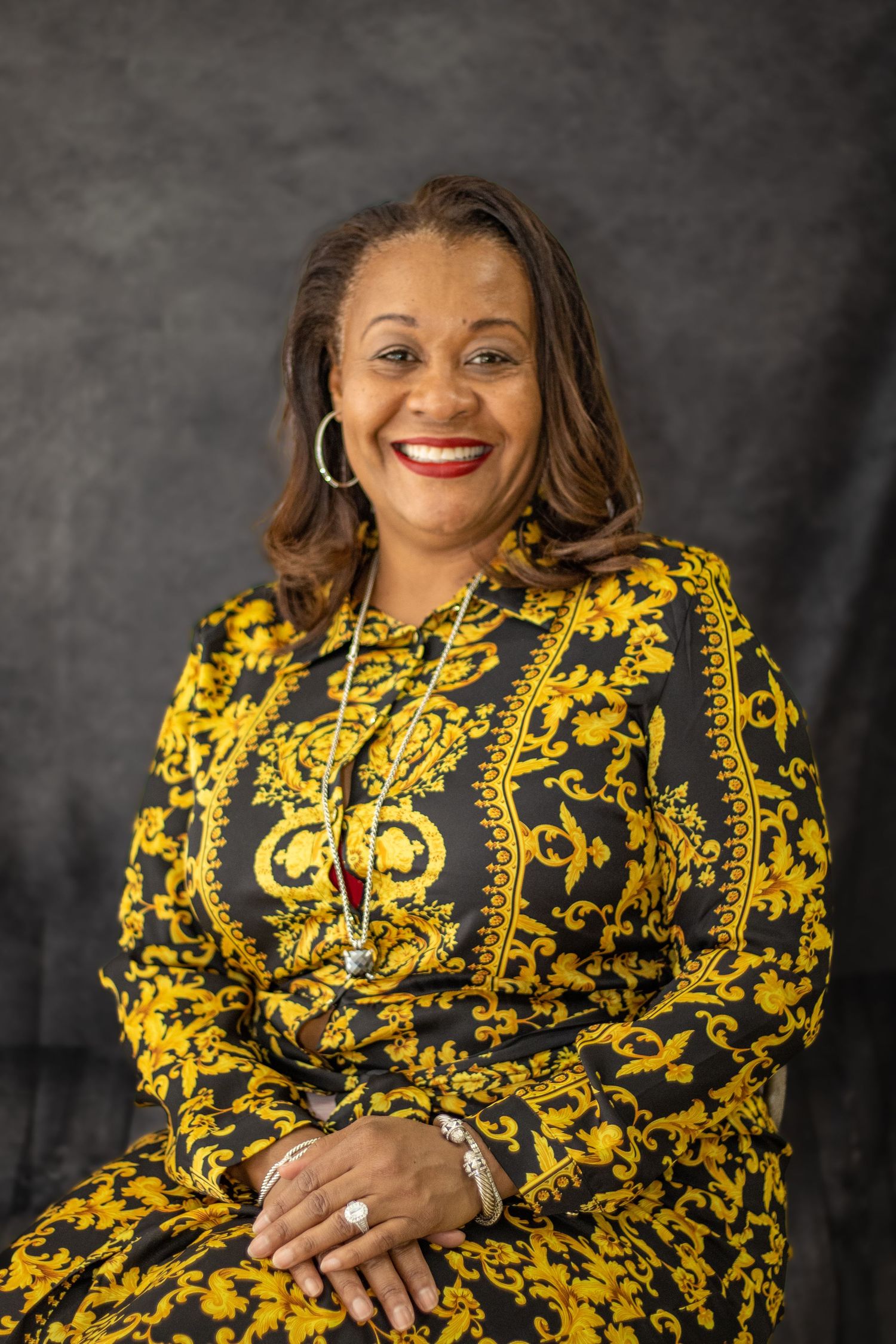 Portrait wearing striking yellow and black patterned dress with statement jewelry.