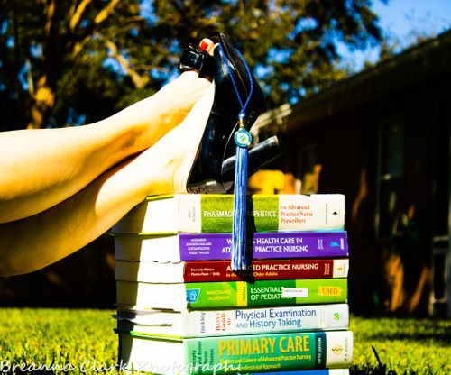 Stack of medical textbooks with black shoes balanced on top in outdoor setting.
