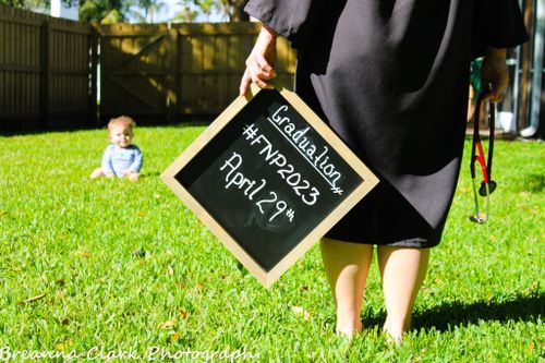 Graduation chalkboard sign held in sunny backyard with green grass.
