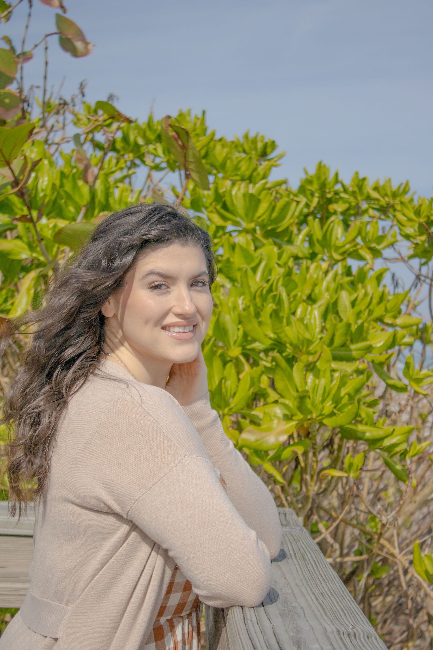 Portrait against lush green foliage with coastal backdrop.