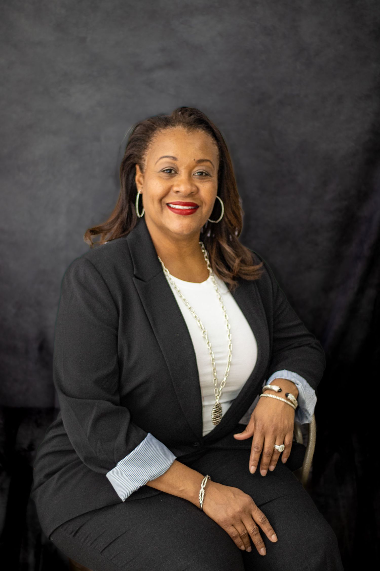 Professional studio photo featuring black blazer, white top and statement jewelry.