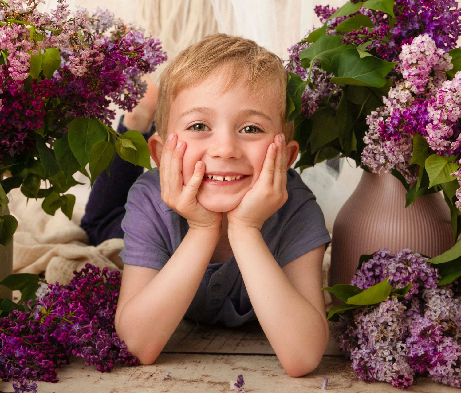 A bright portrait with purple lilac flowers and a joyful expression against a light background.