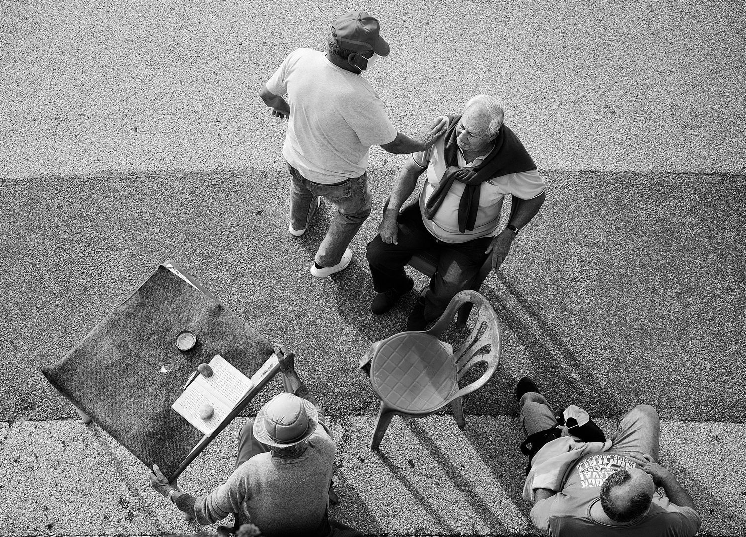 A black and white aerial view of people gathered in a casual social setting outdoors.