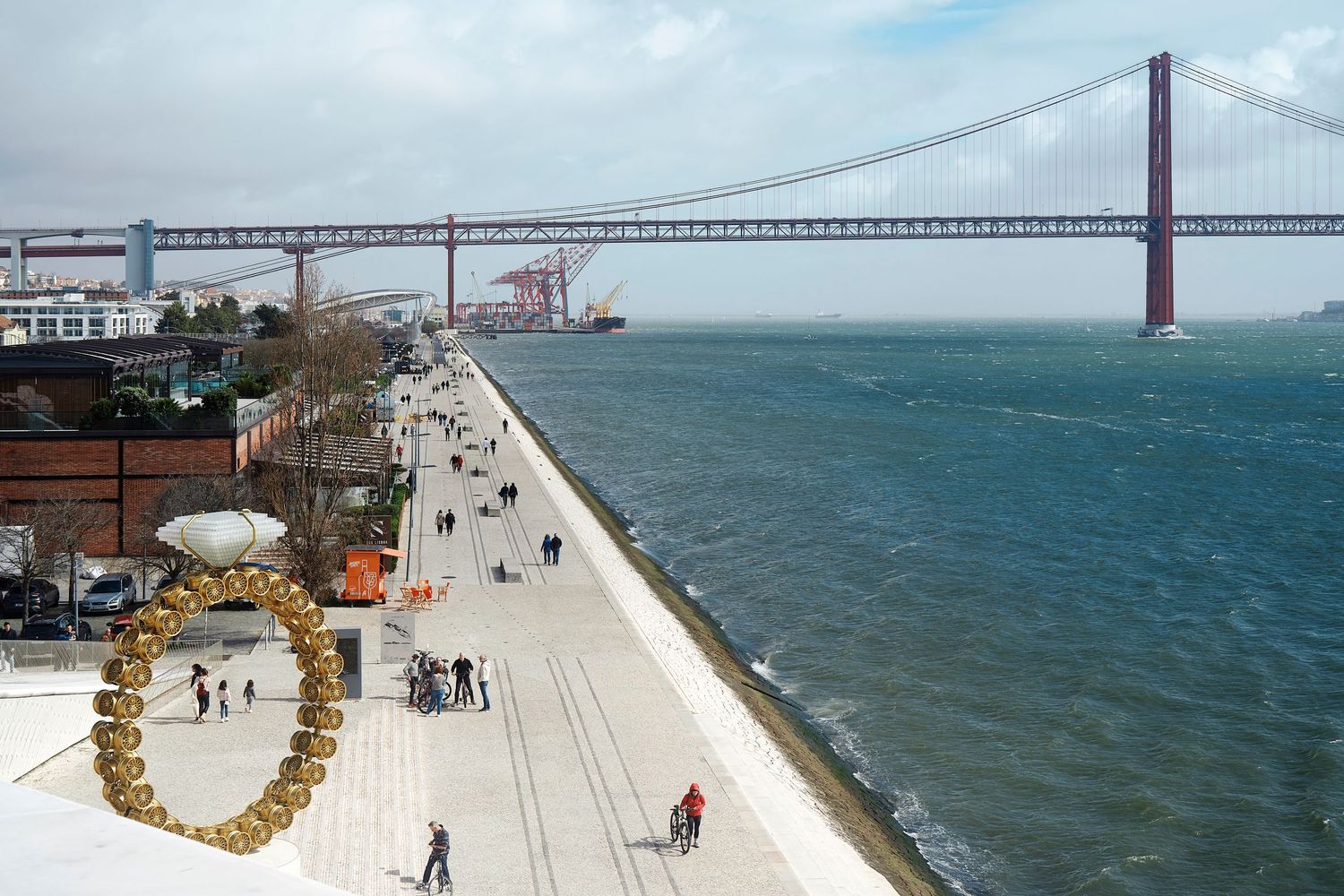 Aerial view of pedestrians walking along the waterfront promenade near the Golden Gate Bridge in San Francisco.