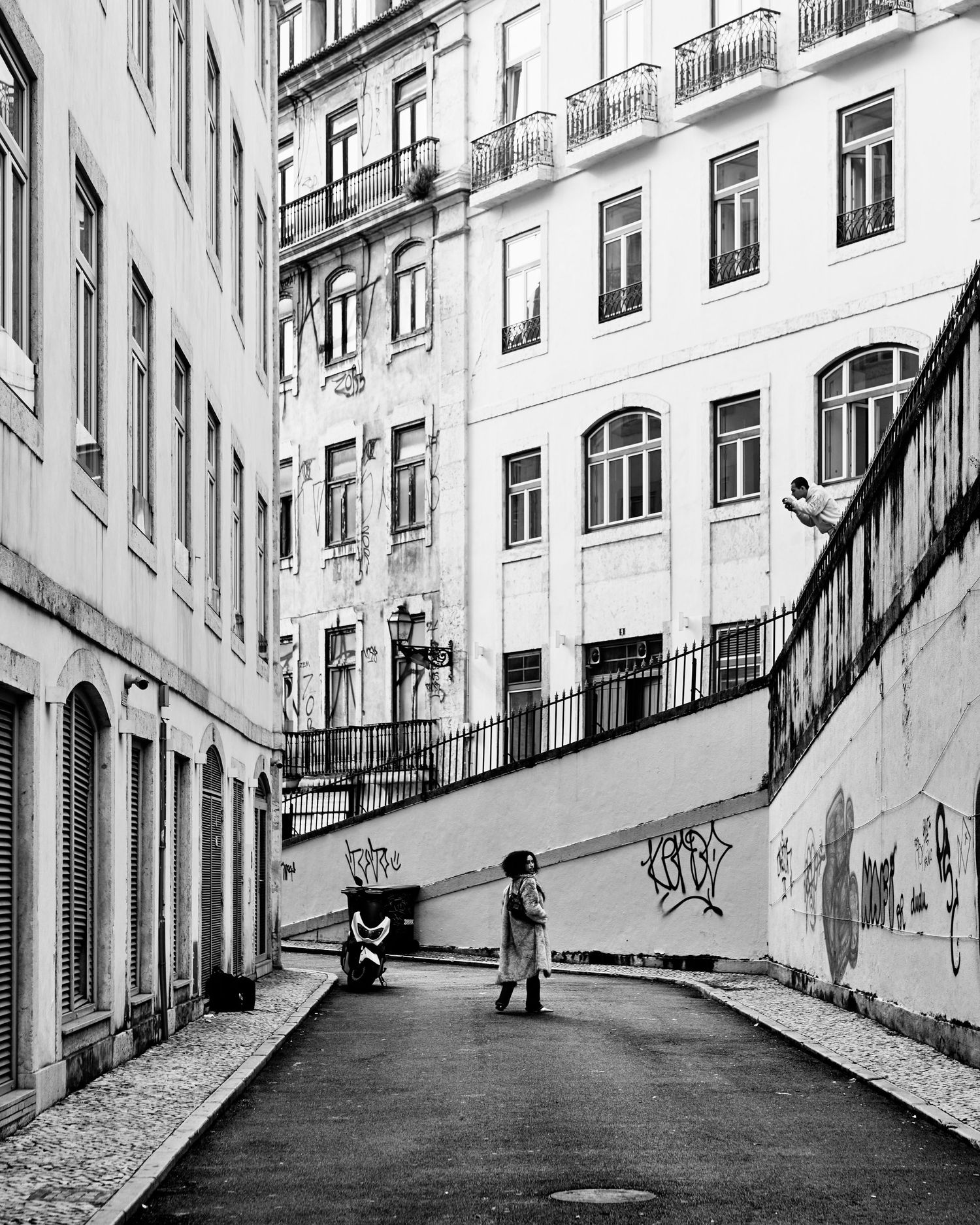 Black and white photo of a steep narrow street between traditional Portuguese buildings.