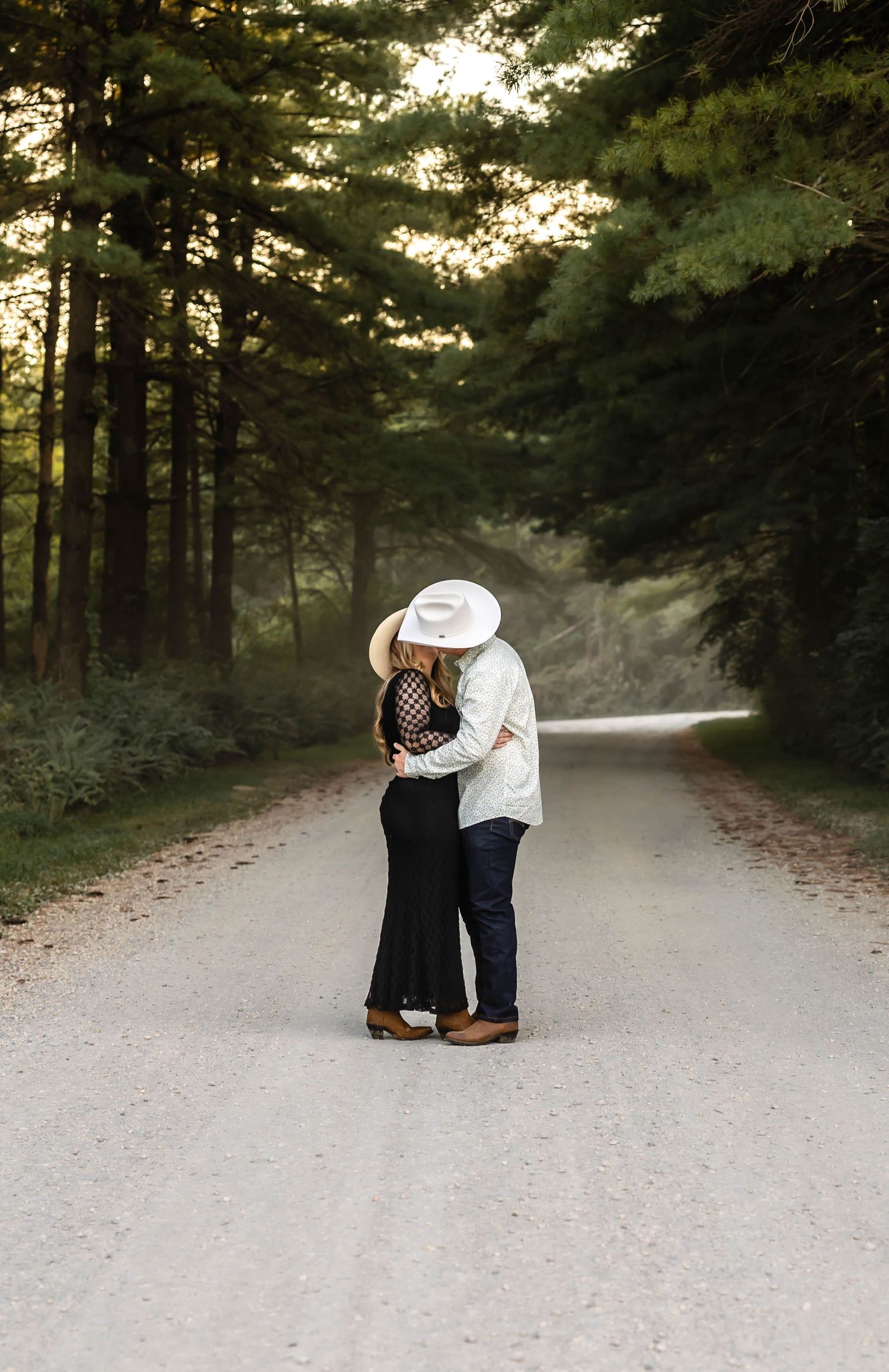 Couple embracing on misty forest path during sunset photo session.