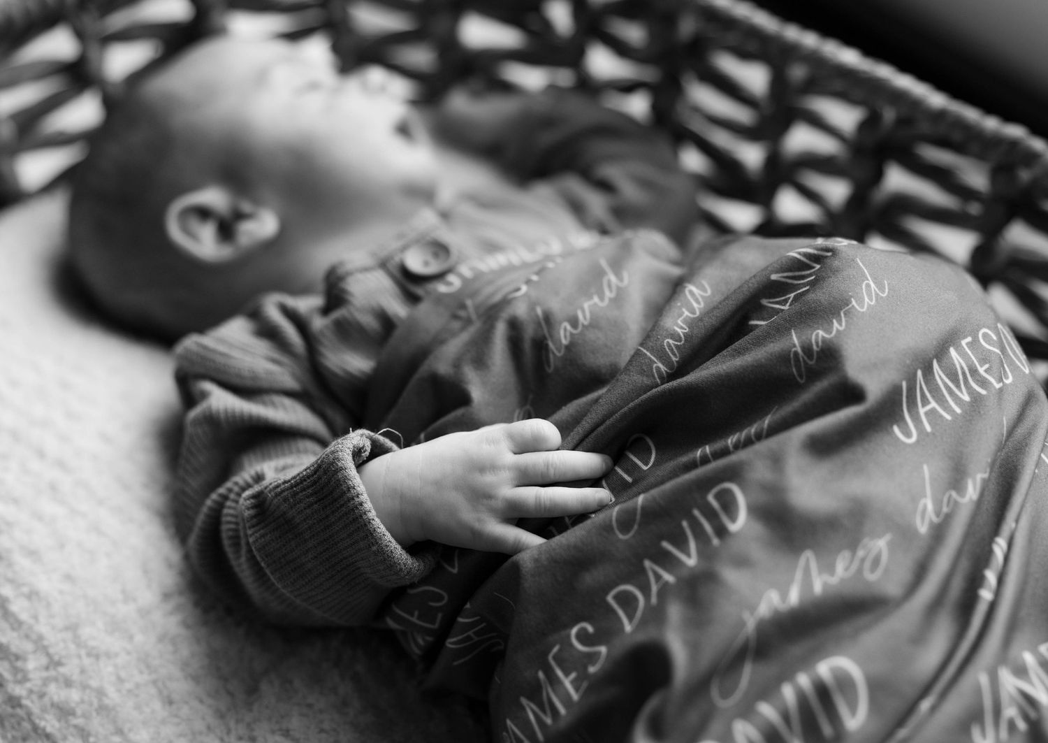 Black and white portrait of sleeping infant in decorated grey outfit.