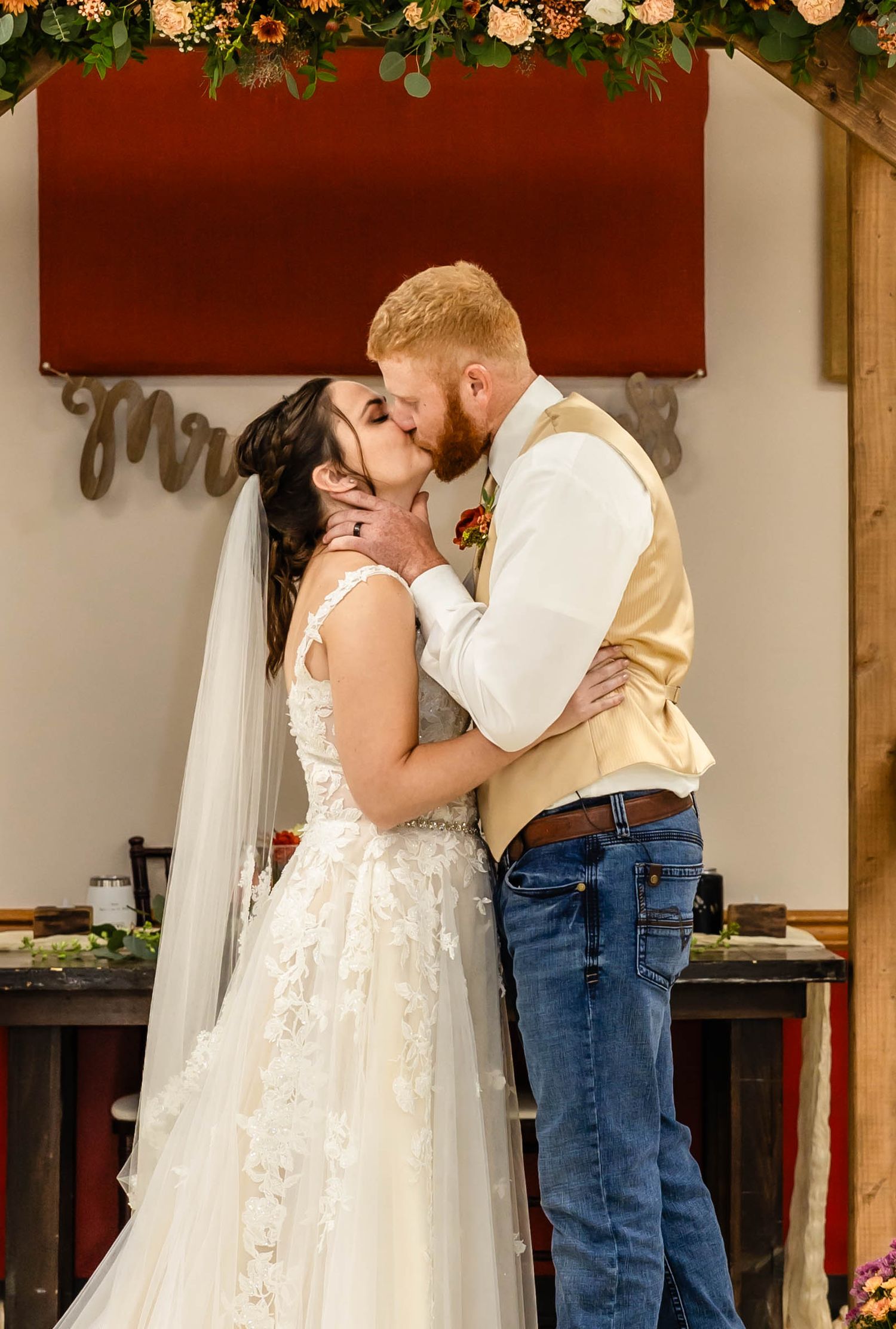 A romantic moment shared between newlyweds under a decorated wooden arch.