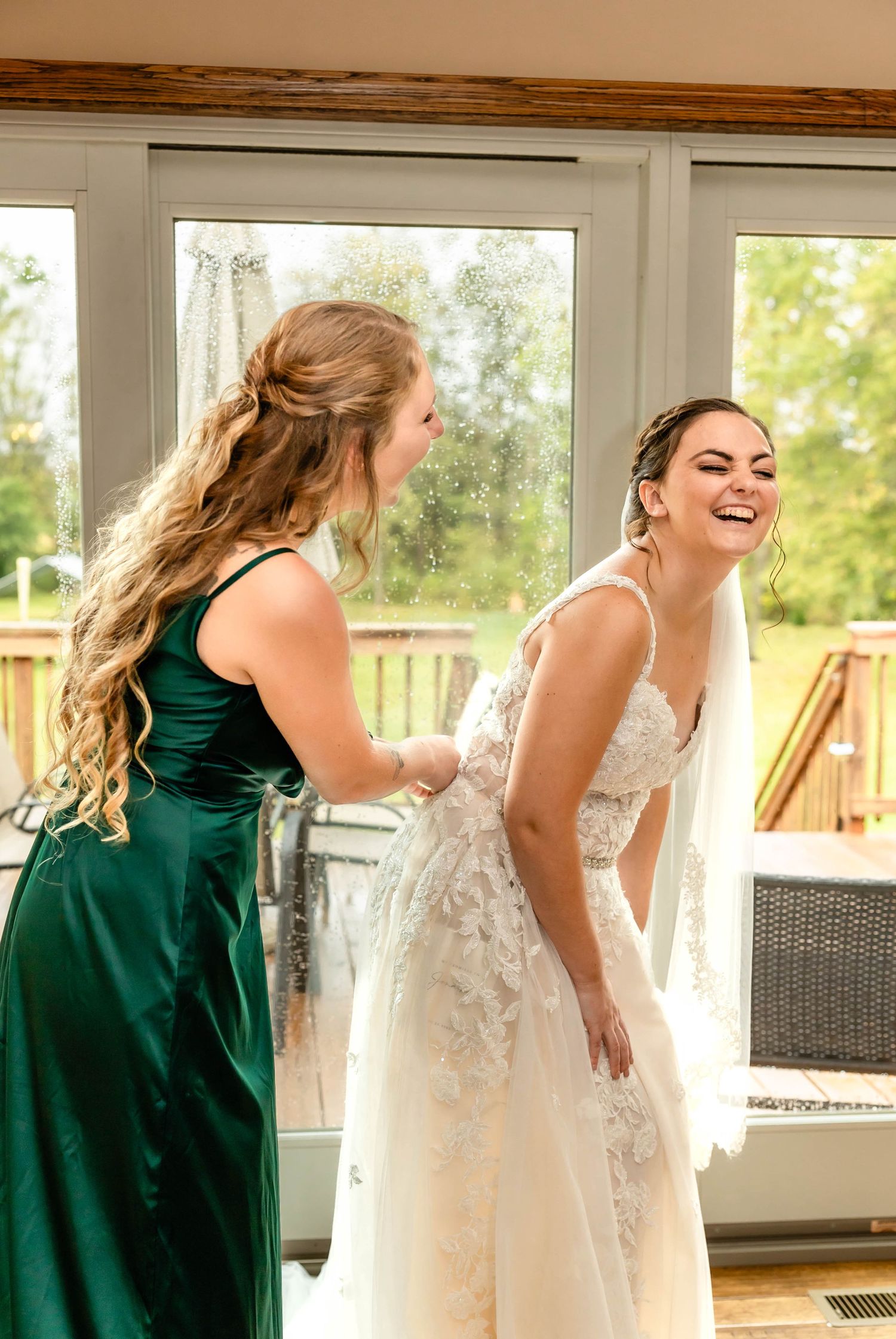 Two women share a joyful moment while finalizing wedding dress preparations.