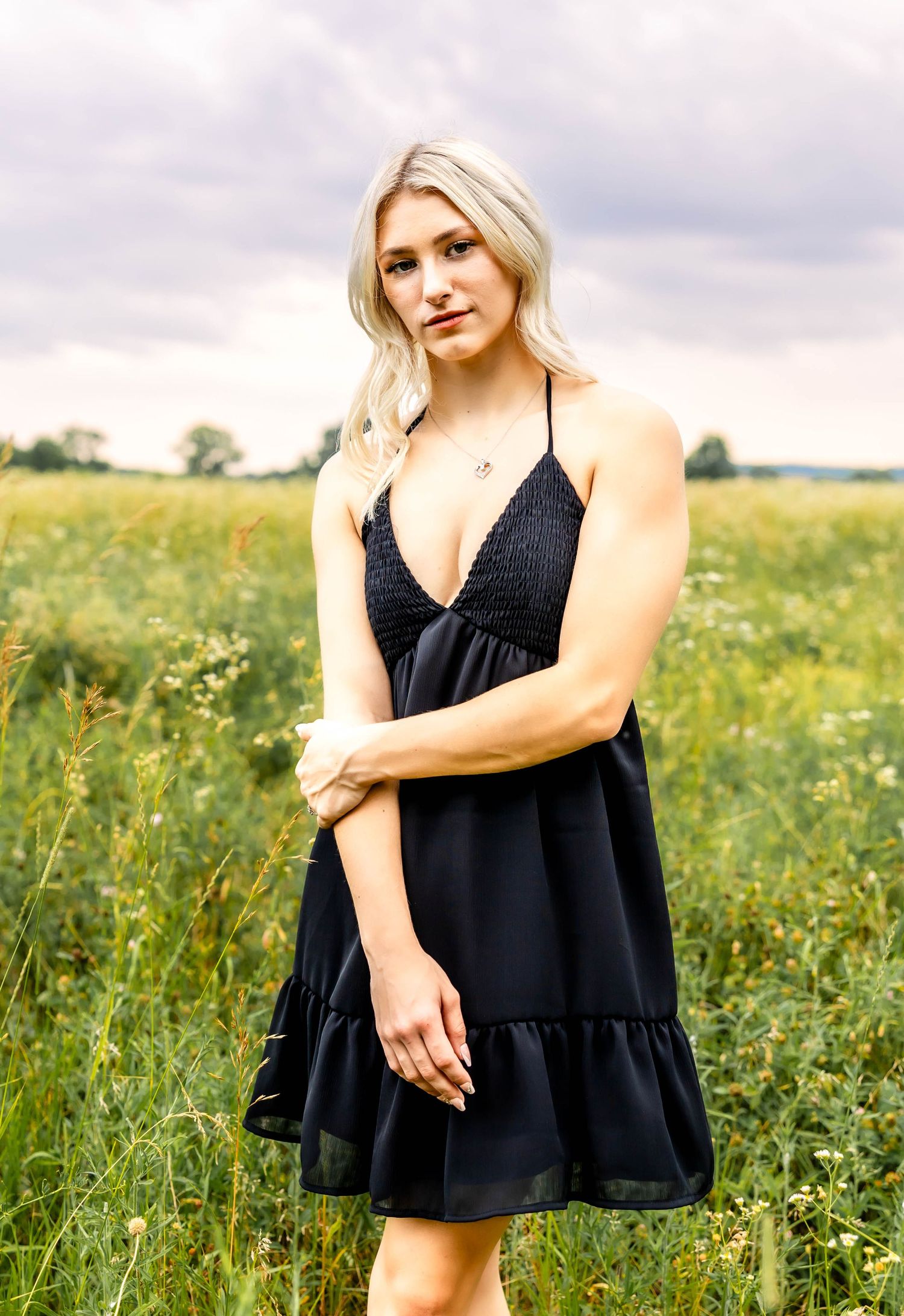 Black v-neck dress with ruffle hem photographed in a meadow setting.