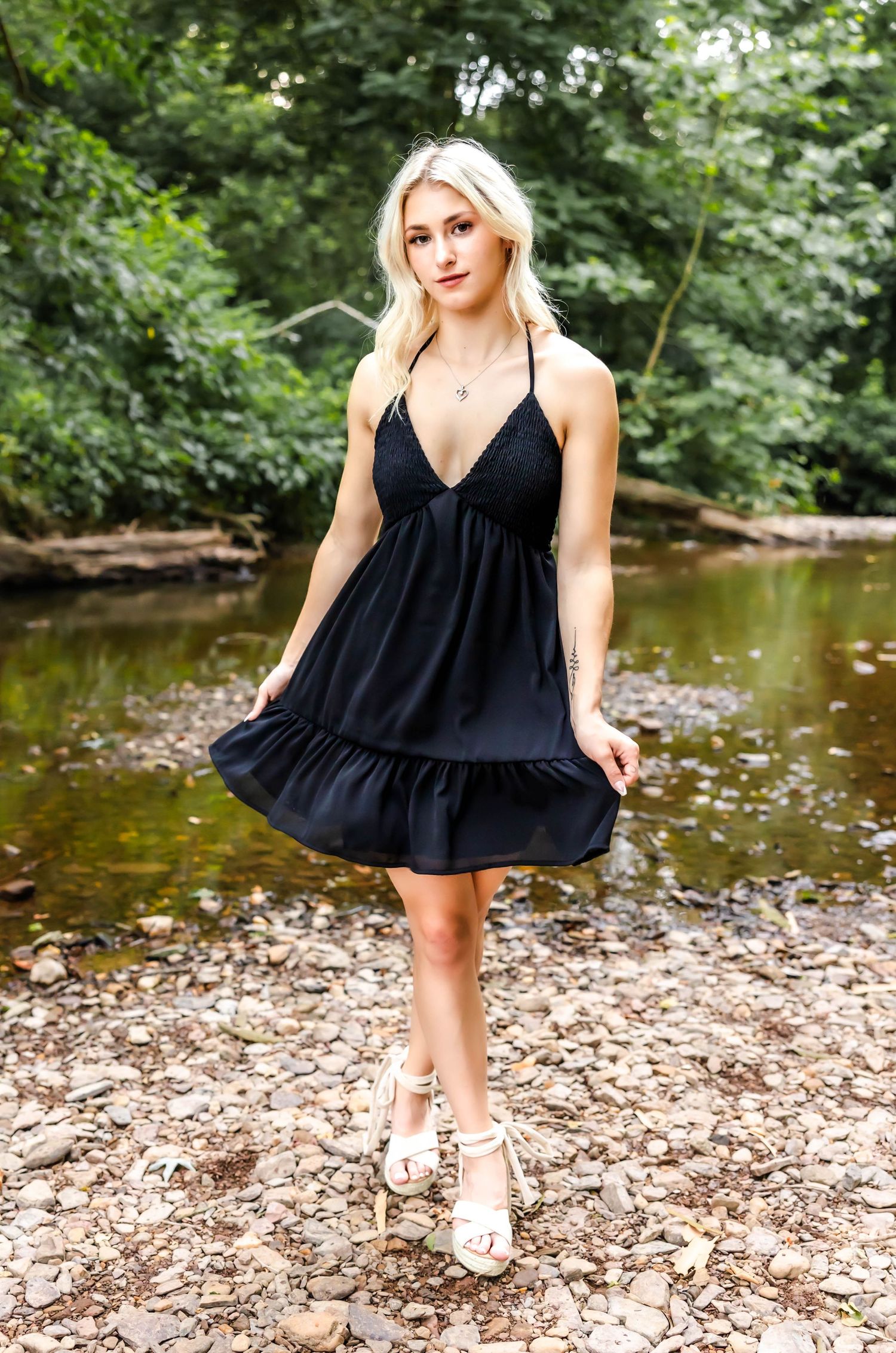 Summer fashion photo of a black dress styled by a creek with natural stone ground.