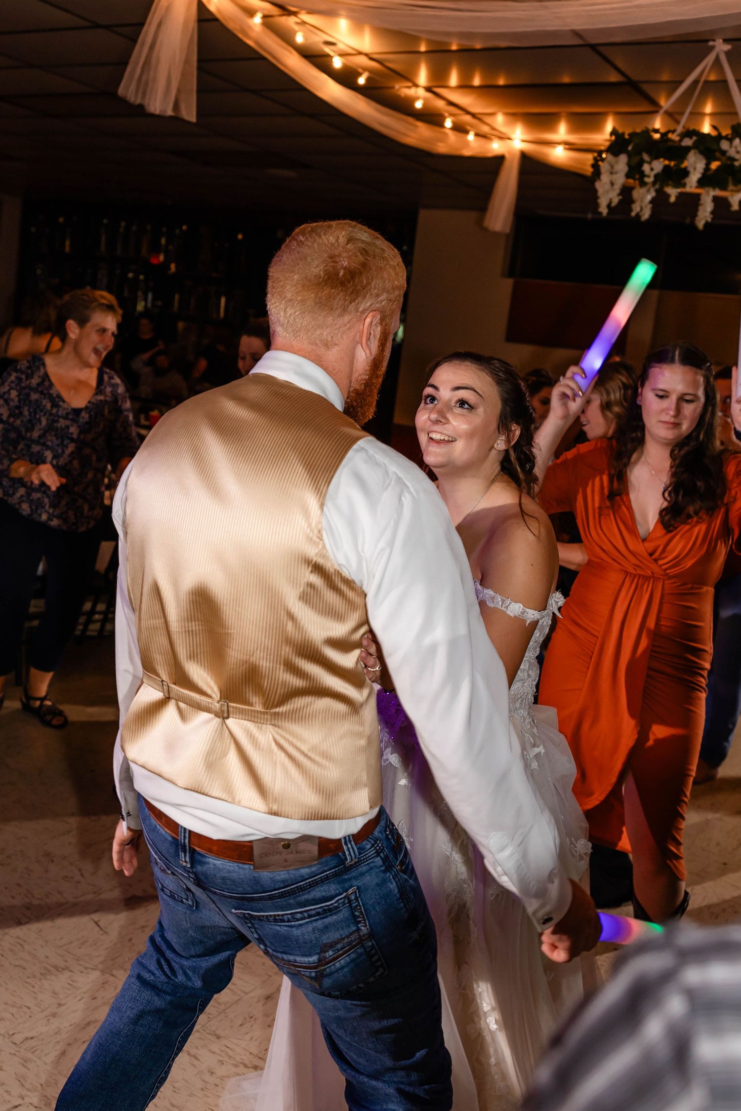 Couple dances with light-up props during lively wedding reception celebration.