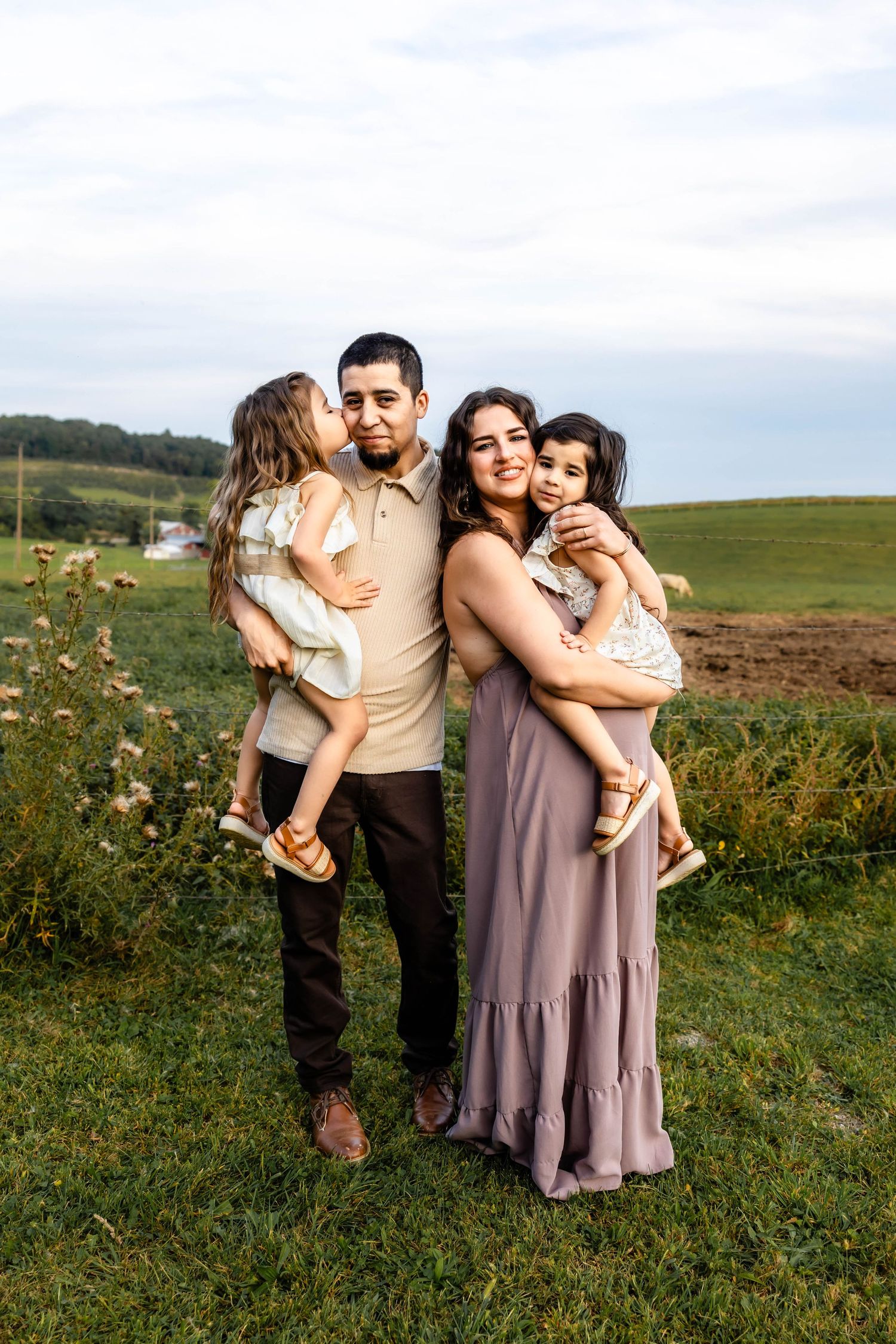 Family sharing tender moment together in sunny countryside field.