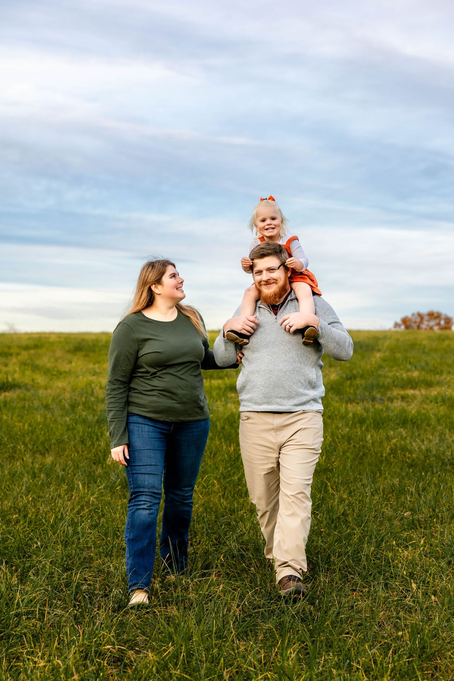 A happy family walks together through a sunny meadow on an autumn afternoon.