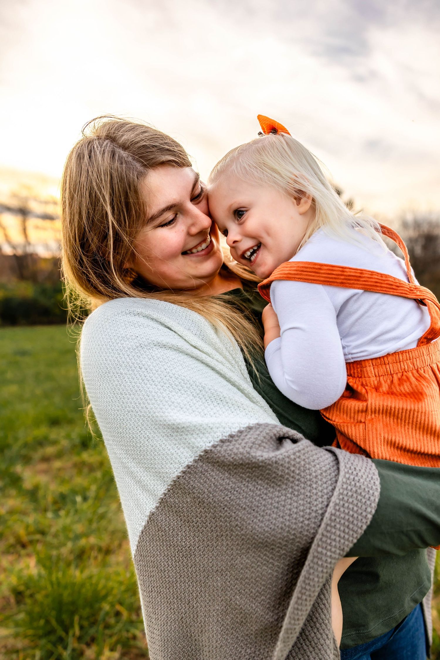 Natural laughter shared between mother and child during sunset photo session.