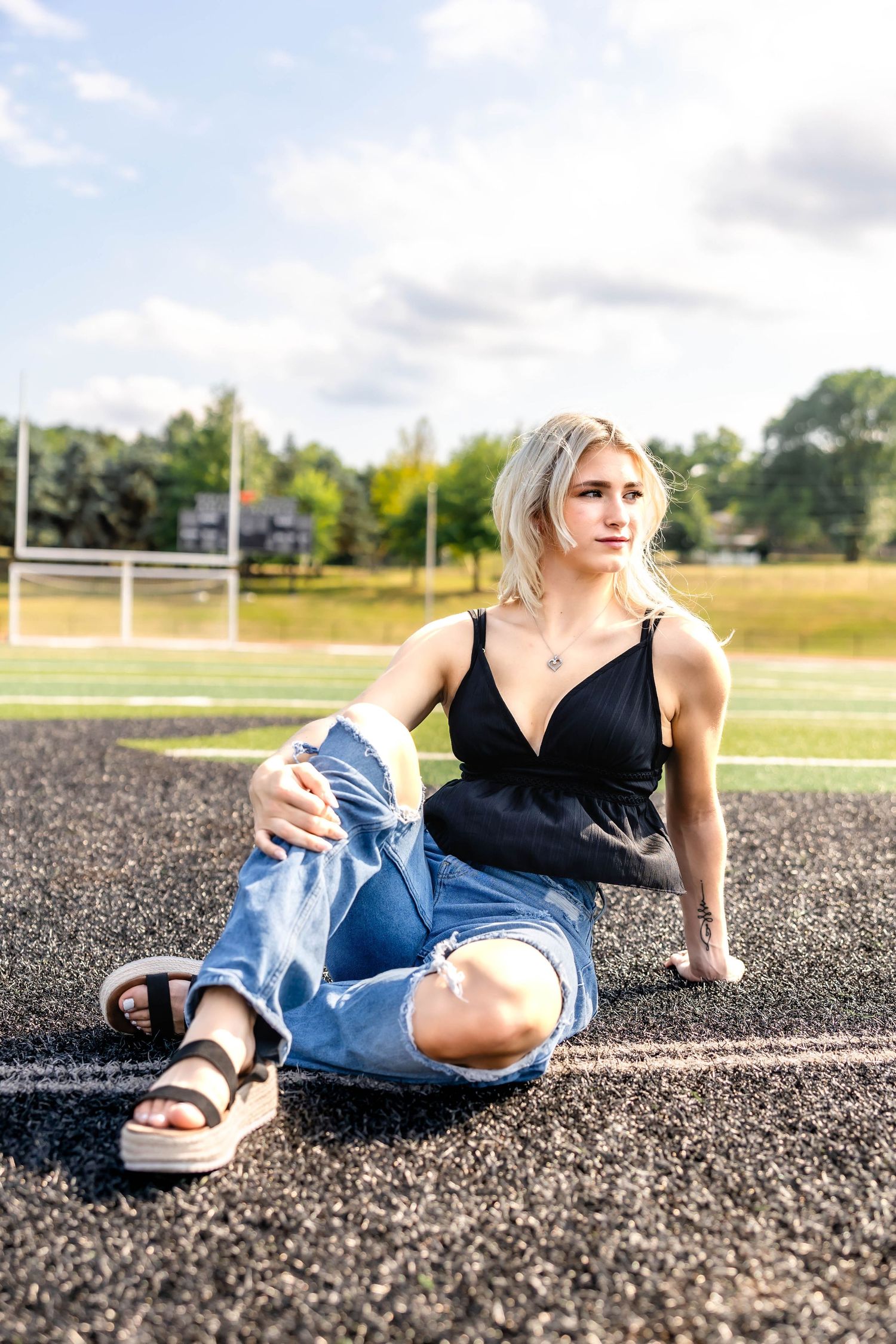 Summer fashion shoot on sports field showing black peplum top and distressed denim.