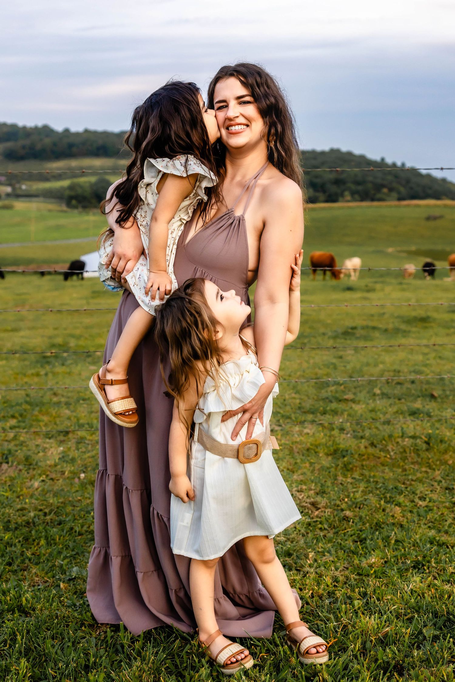 A joyful outdoor family moment against a backdrop of rolling hills and farmland.