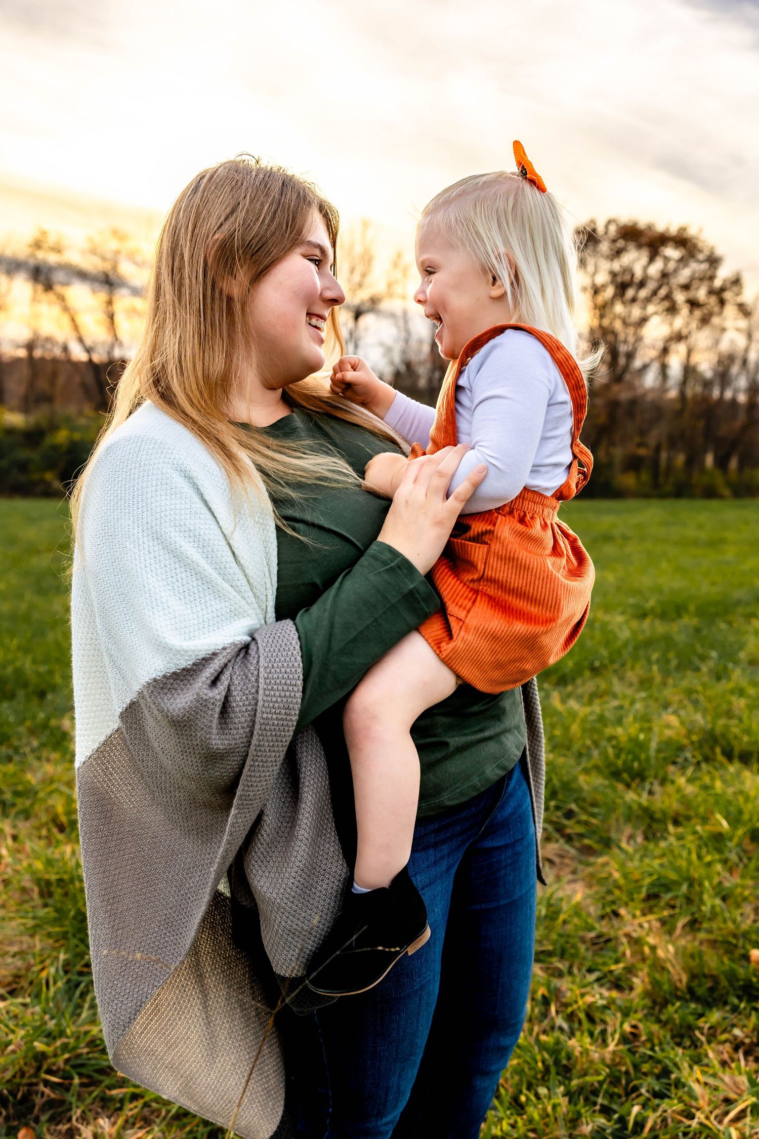 Mother and child share playful moment outdoors during golden hour.