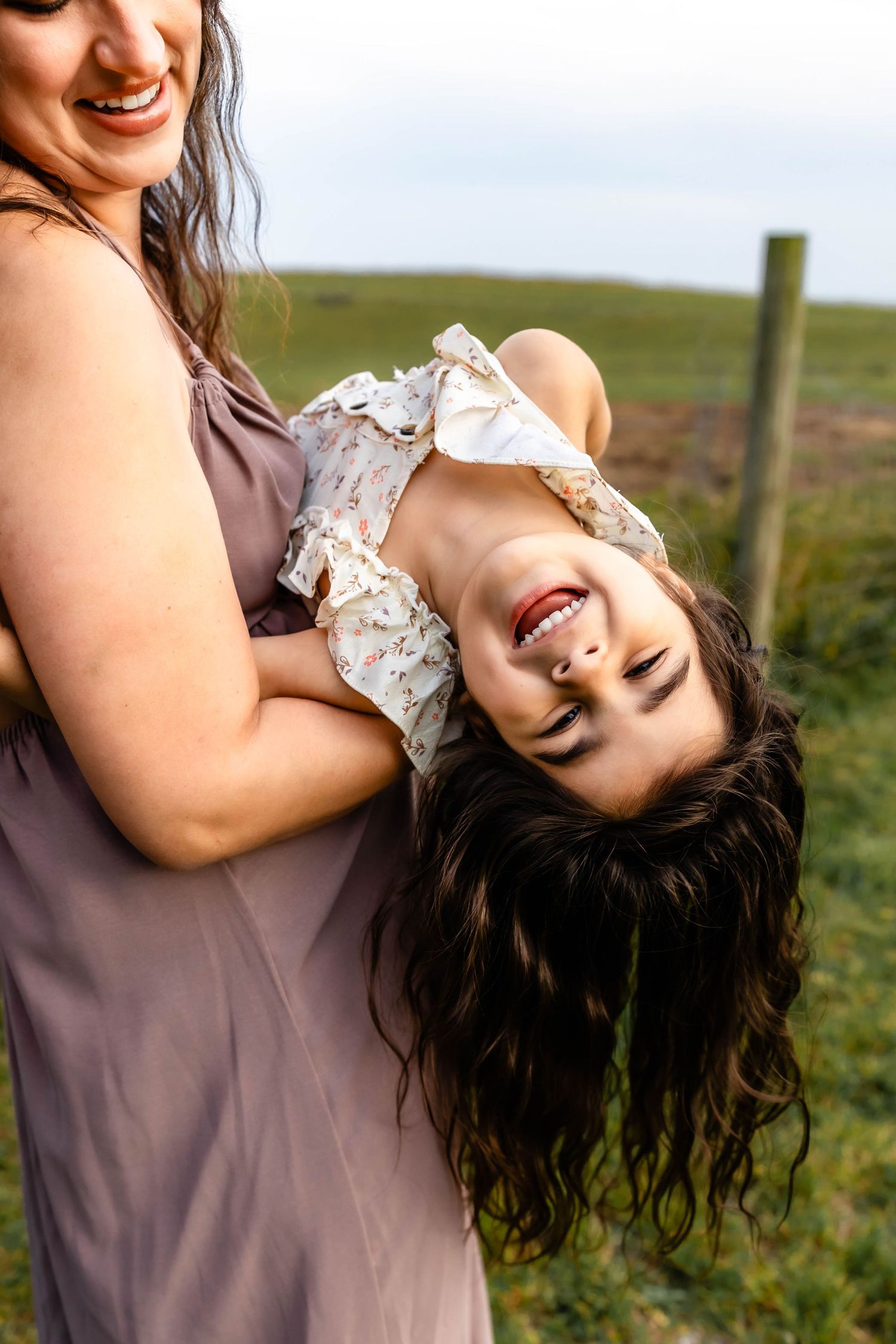 A candid moment of laughter and play as a child is held upside down outdoors.