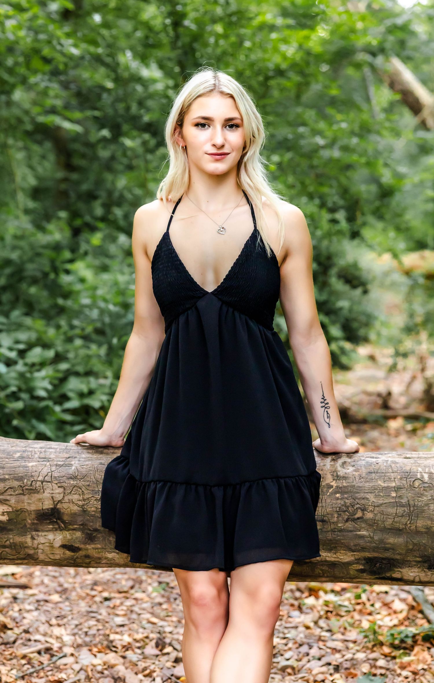 A black halter dress being modeled in a woodland setting with greenery in the background.