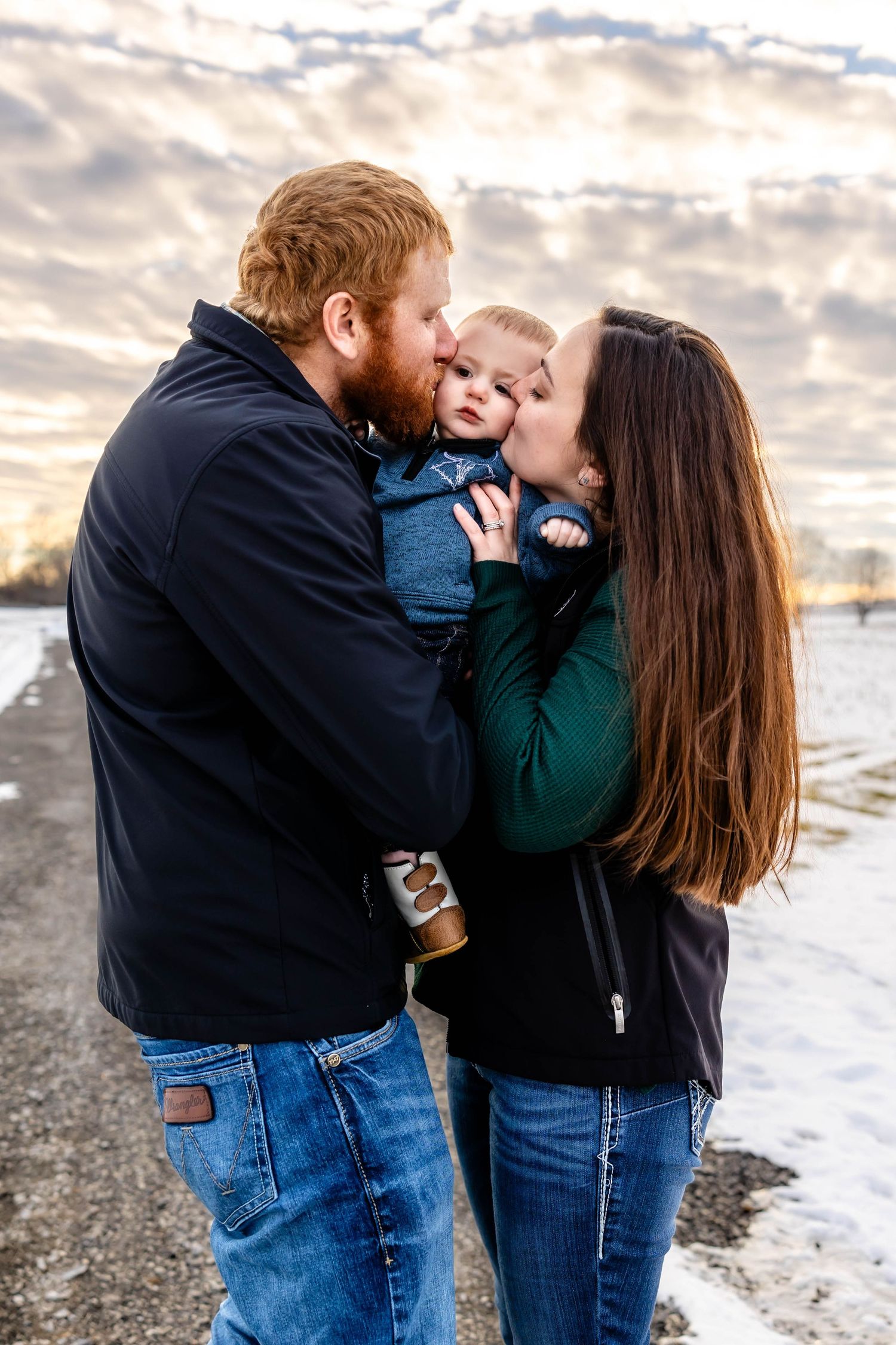 A tender family moment shared between three people against a dramatic winter sunset sky.