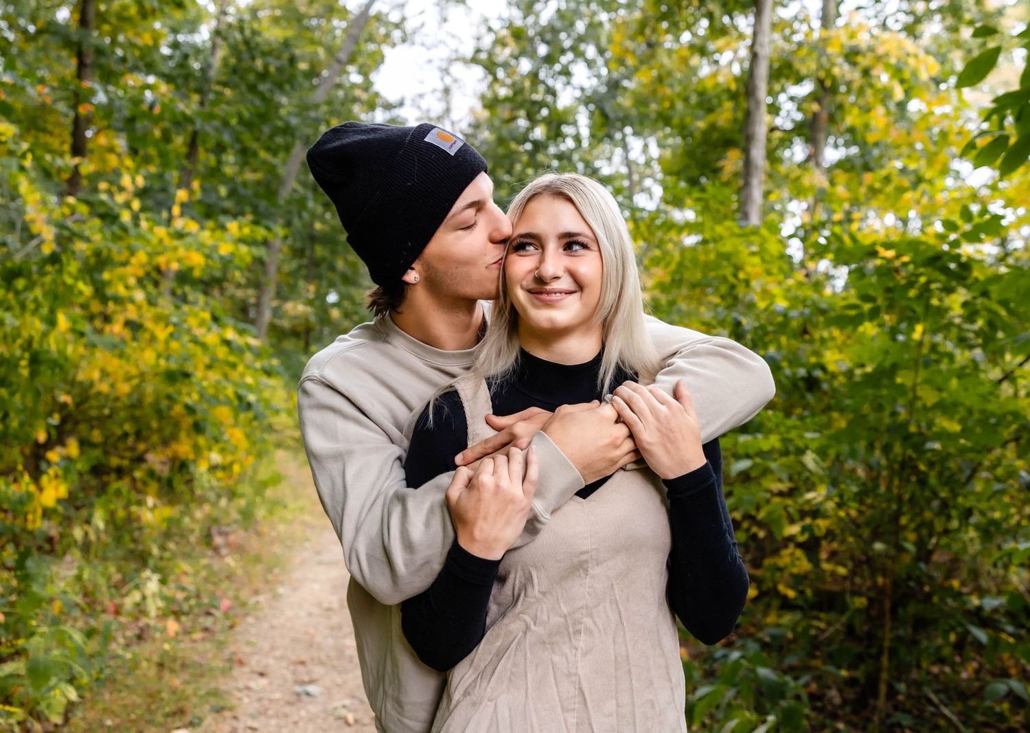 Intimate outdoor portrait of couple embracing against autumn trees.
