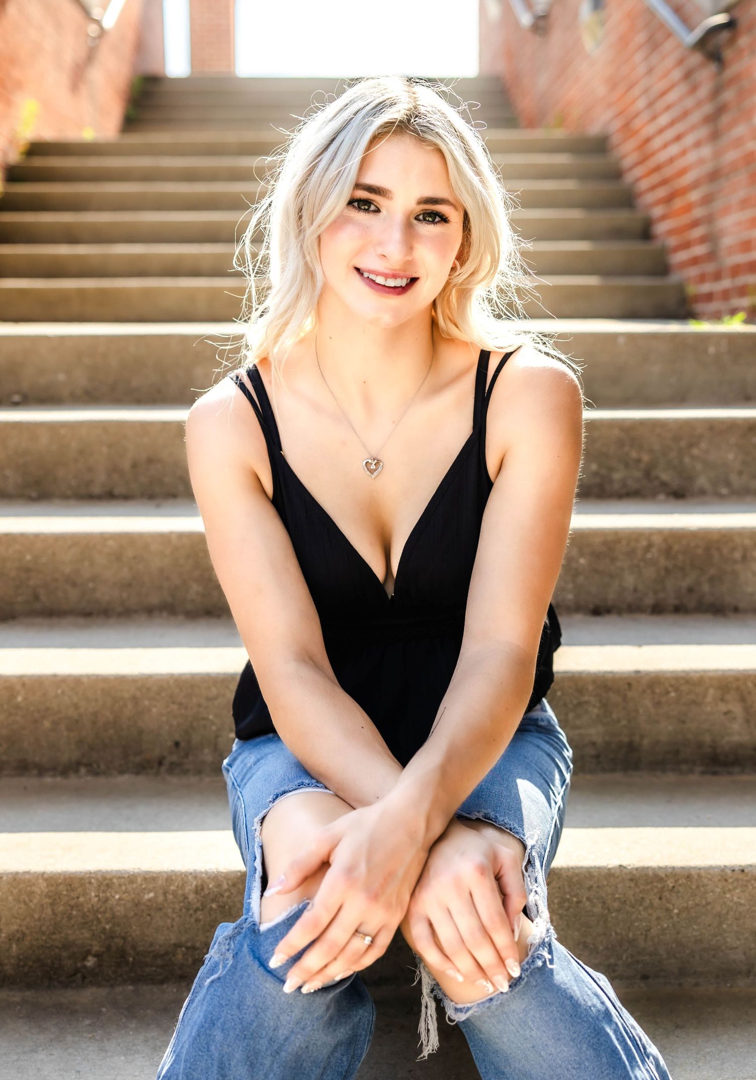 Bright summer portrait on concrete steps with brick wall background.