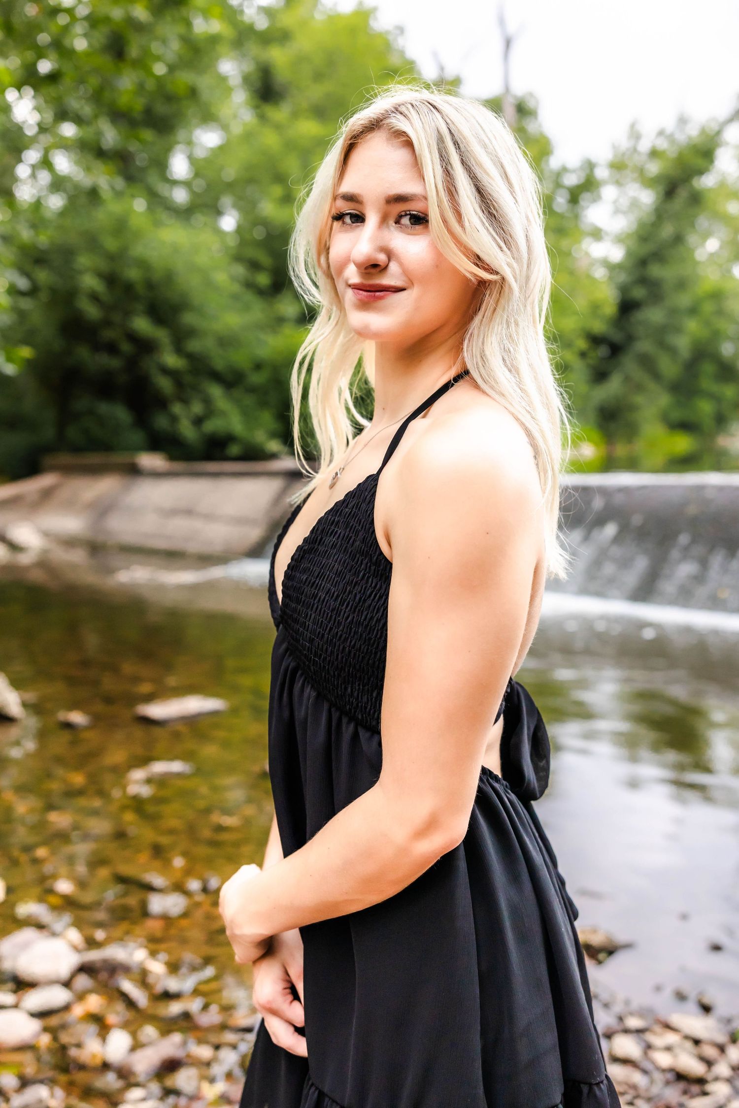 A black summer dress is showcased against a scenic waterfall background.