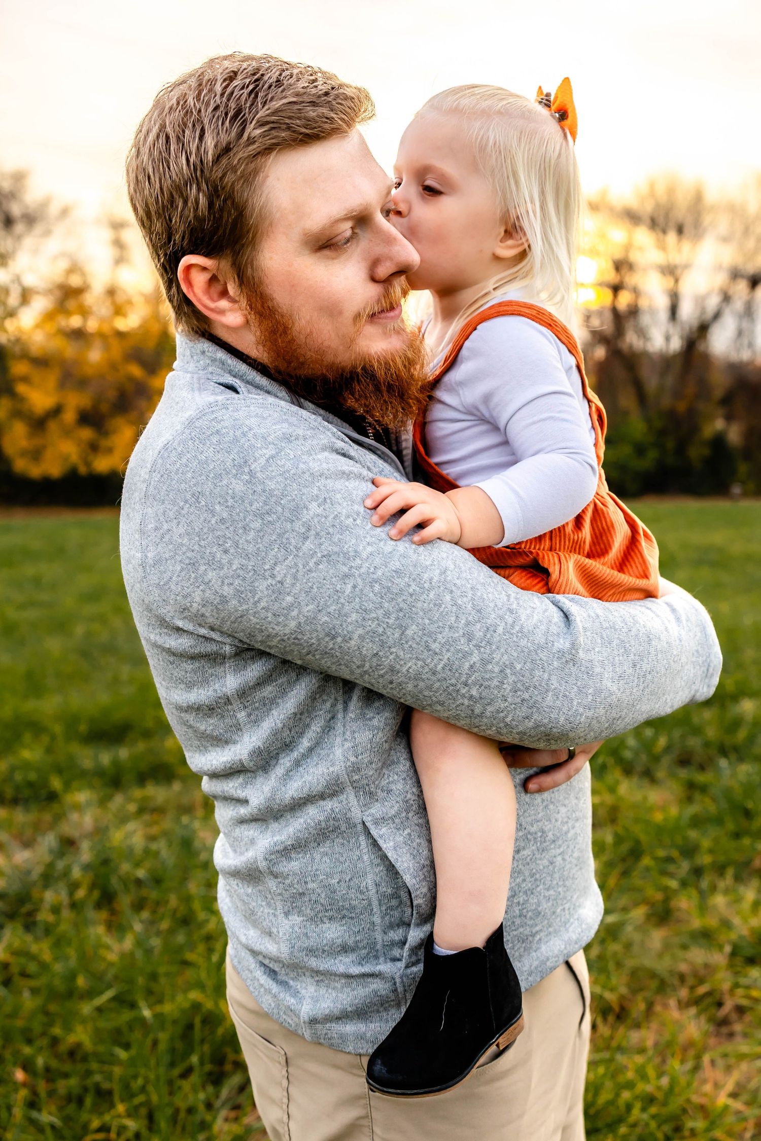 Intimate family moment captured during golden hour showing affectionate embrace in outdoor setting.