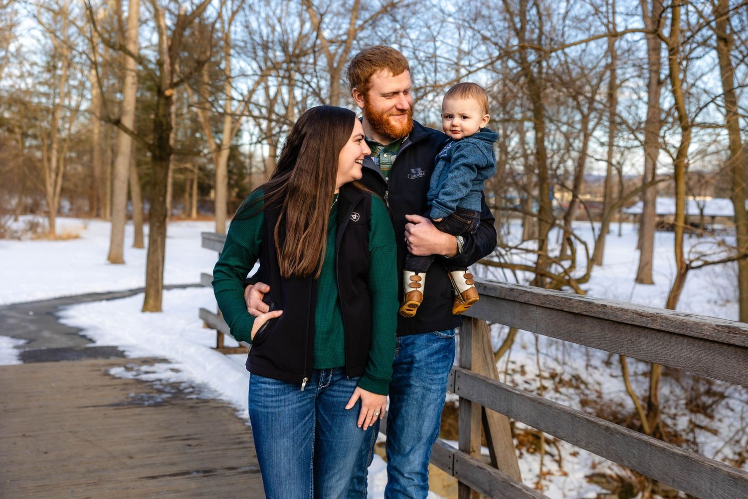 Happy group poses on wooden bridge with snow-covered trees in background.