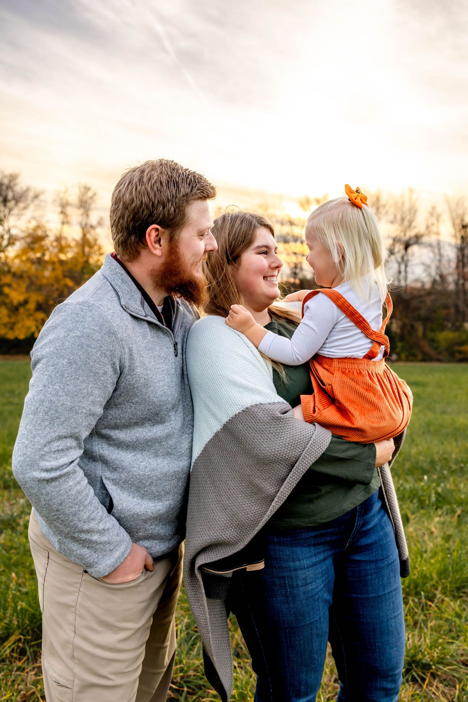 Family enjoying golden hour outdoors together in a grassy field.