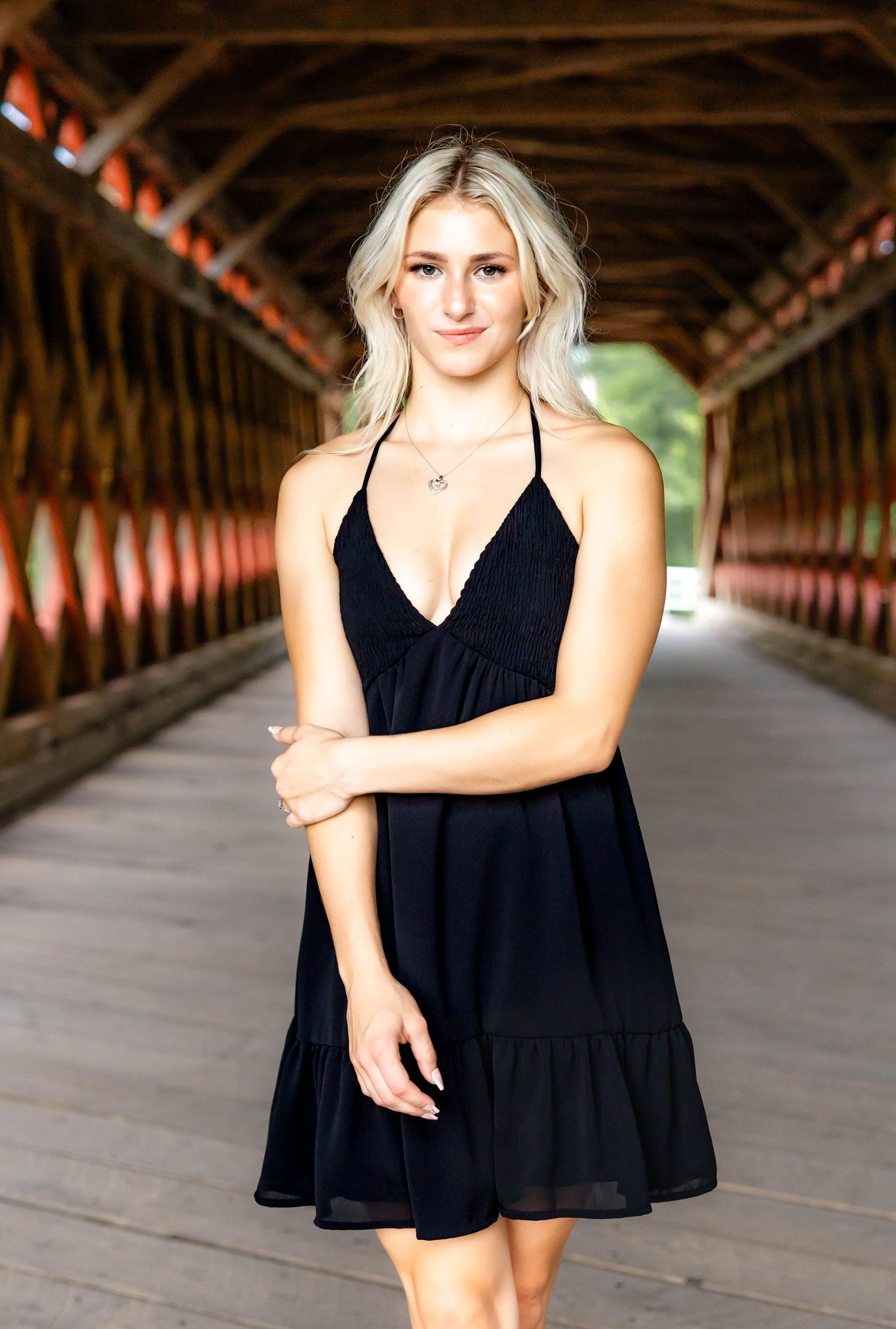 Black summer dress and blonde hair photographed in a rustic covered bridge setting.