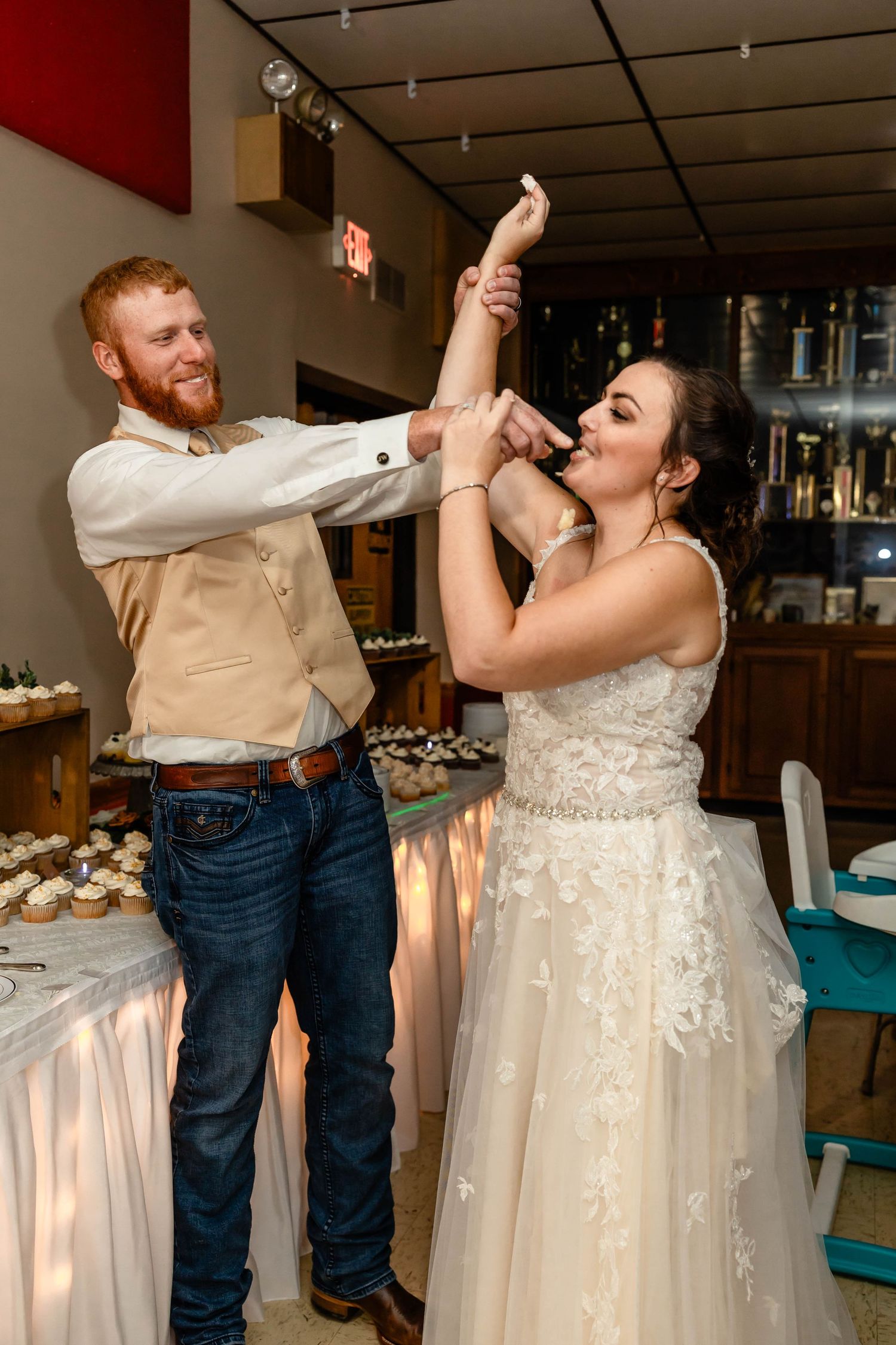 The couple playfully feeds each other wedding cake during their reception celebration.