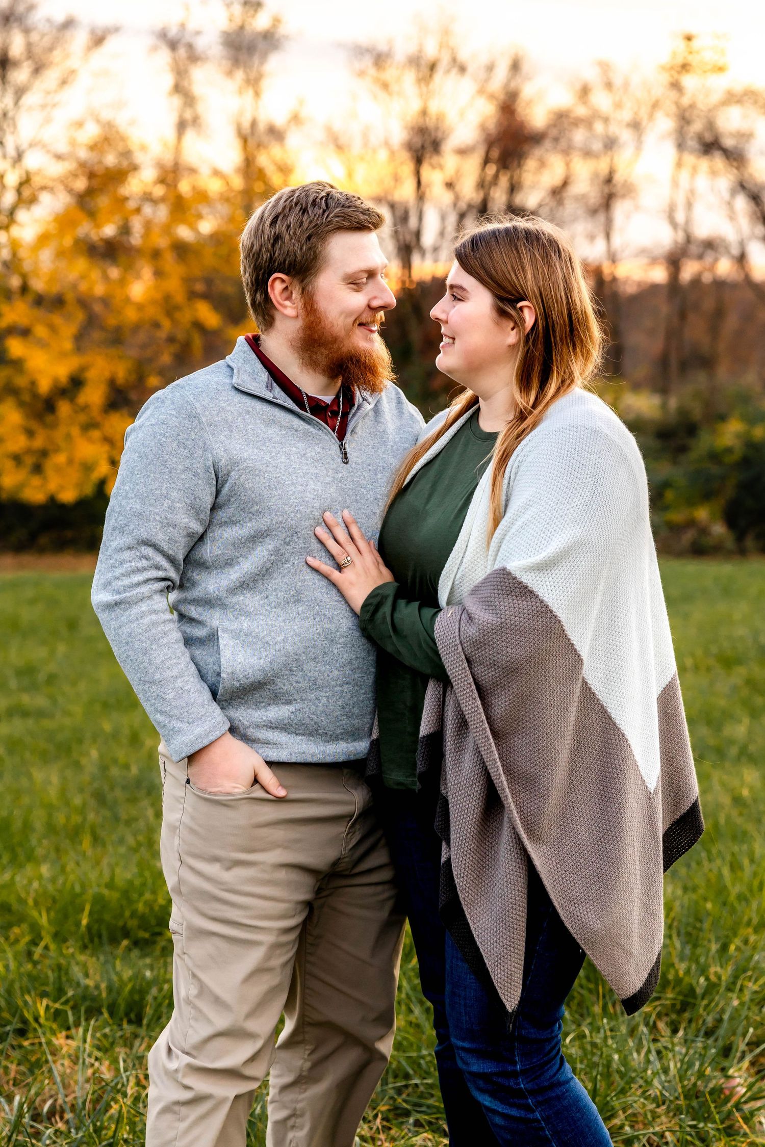 A romantic couple shares an intimate moment outdoors during autumn with golden foliage in the background.