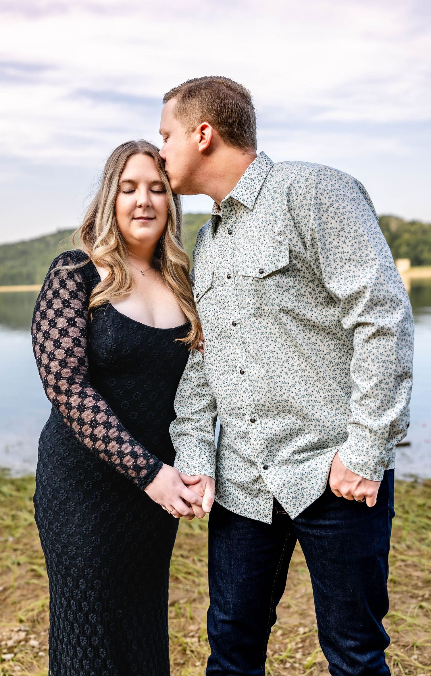 Intimate lakeside portrait of couple in casual attire during engagement session.