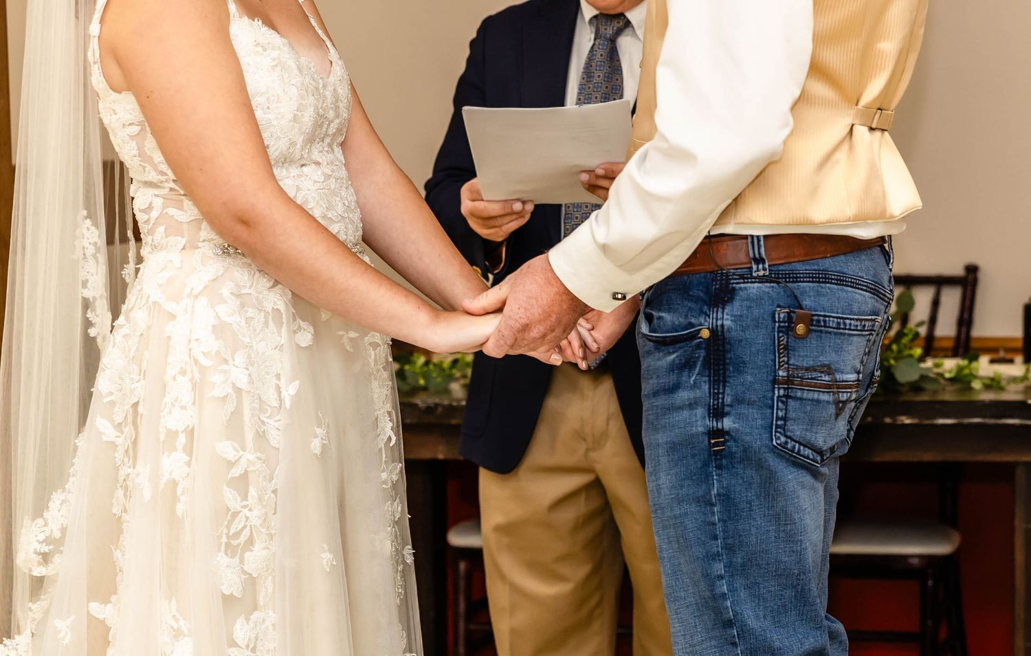 Close up of joined hands during an indoor wedding ceremony.