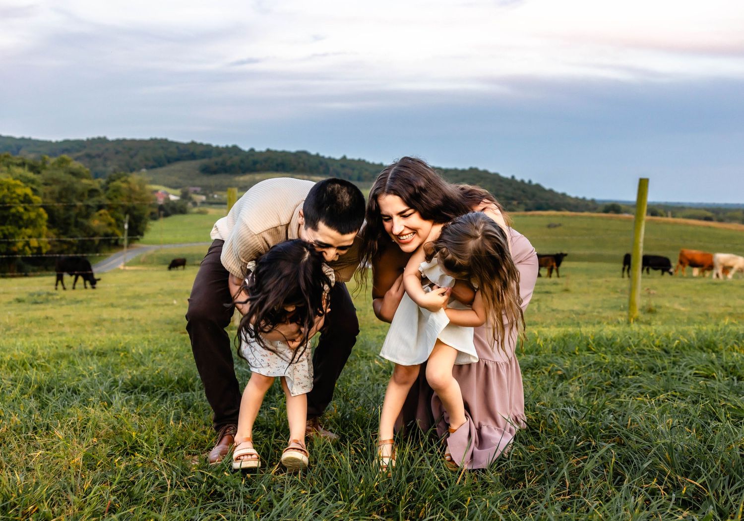 Group laughing together while standing in a green pasture with mountains and cattle visible in the distance.